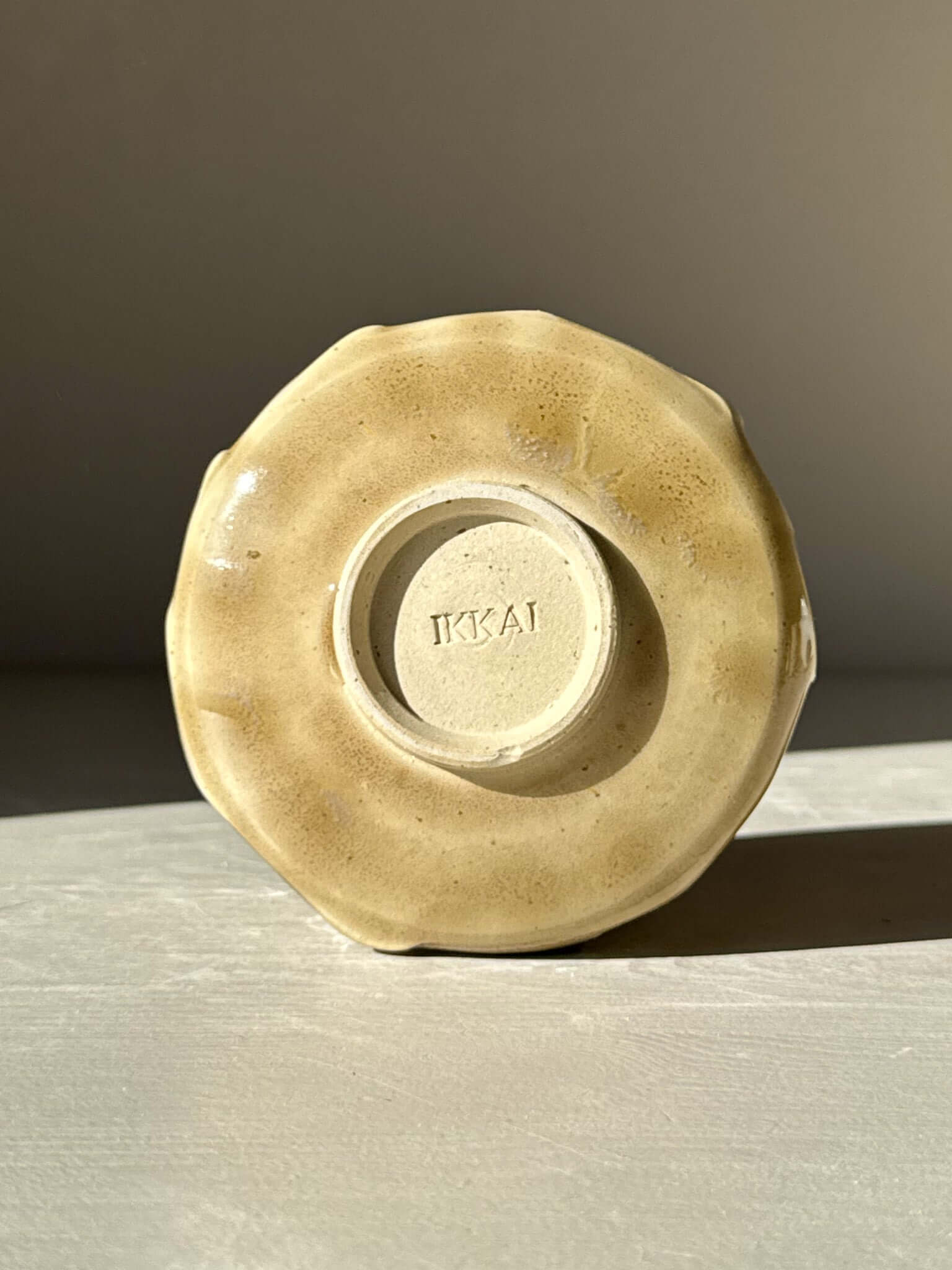 Bottom view of Yunomi Cup - Beige showcasing the stamped base and subtle beige glaze with flowing slip texture for a natural look.