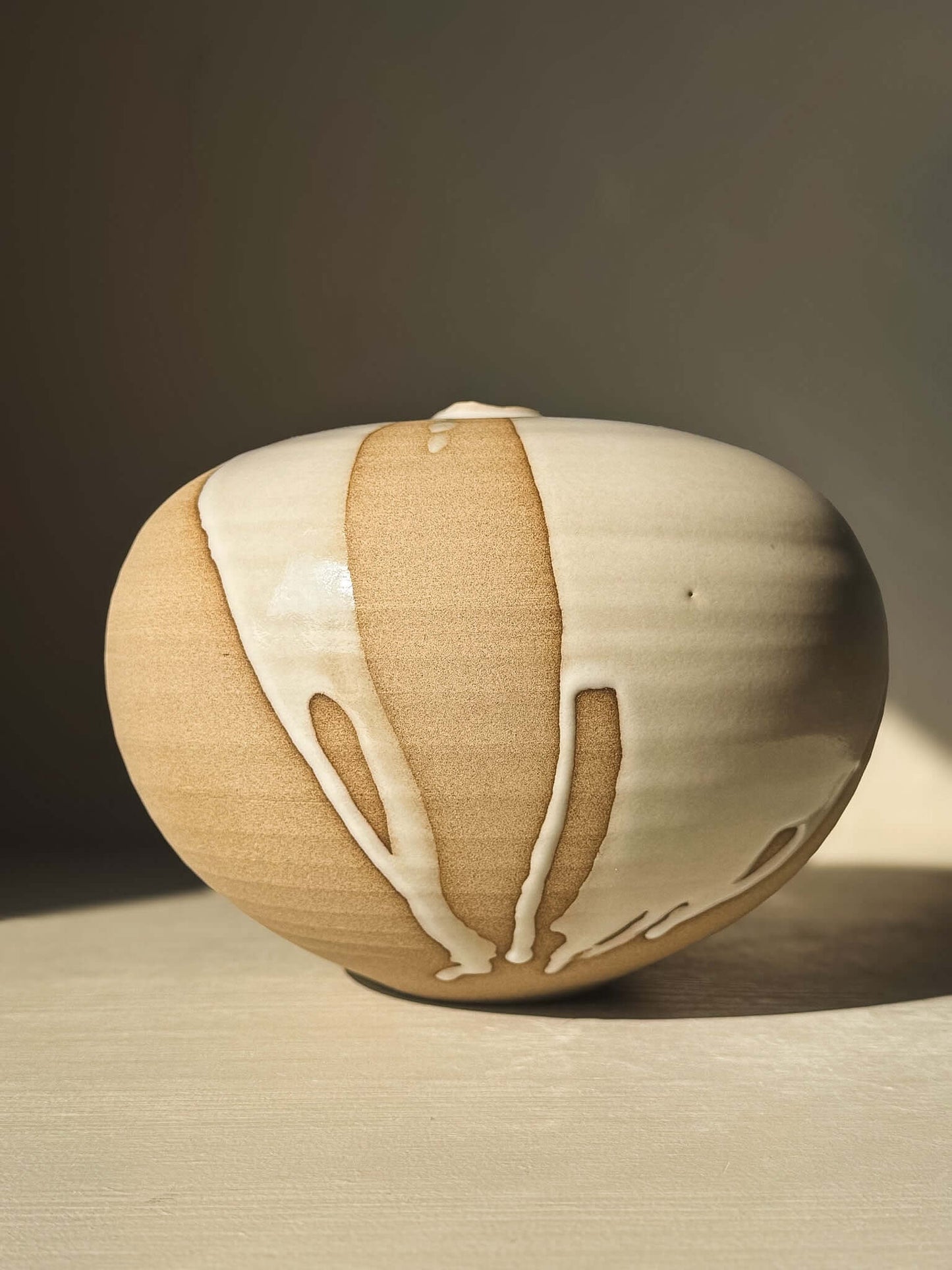 Orb Vase – #19 with unique glaze patterns and soft spherical design, showcasing its sculptural presence in a warm setting.