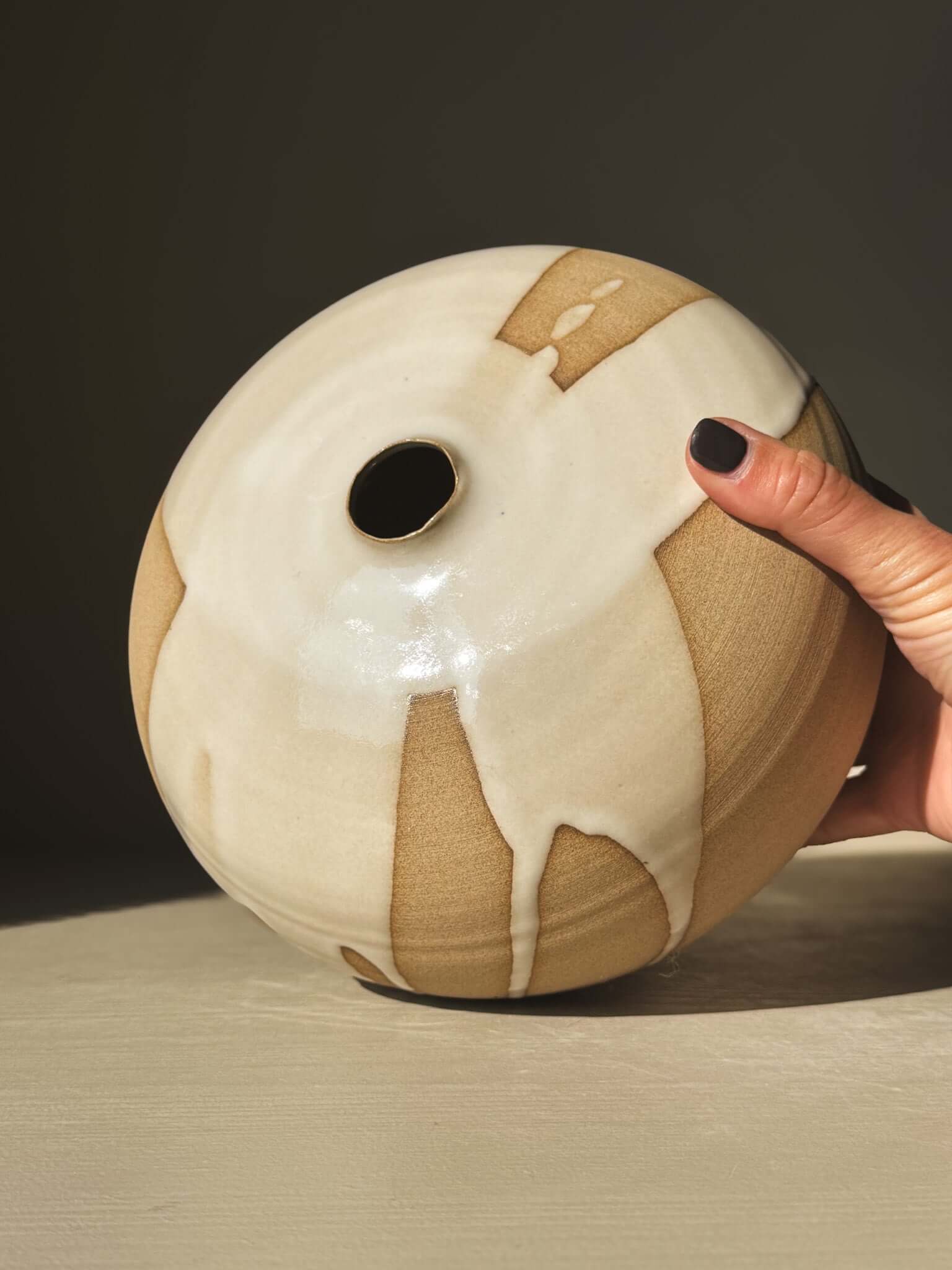 Hand holding Orb Vase – #19 with natural glaze drips and sculptural presence.