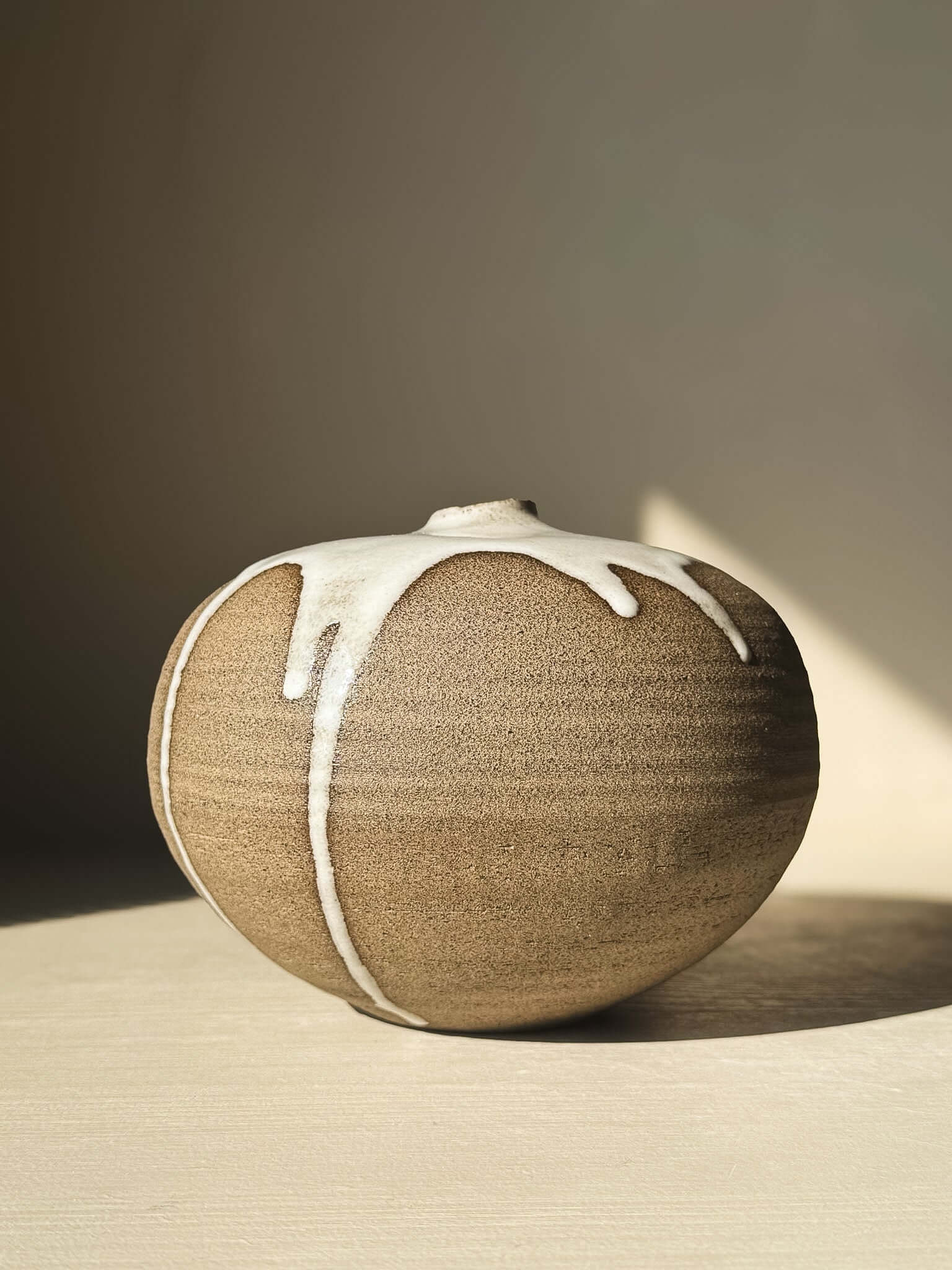 Orb Vase – #17 with a soft spherical form and unique glaze drips, showcasing a calm, sculptural presence in neutral tones.