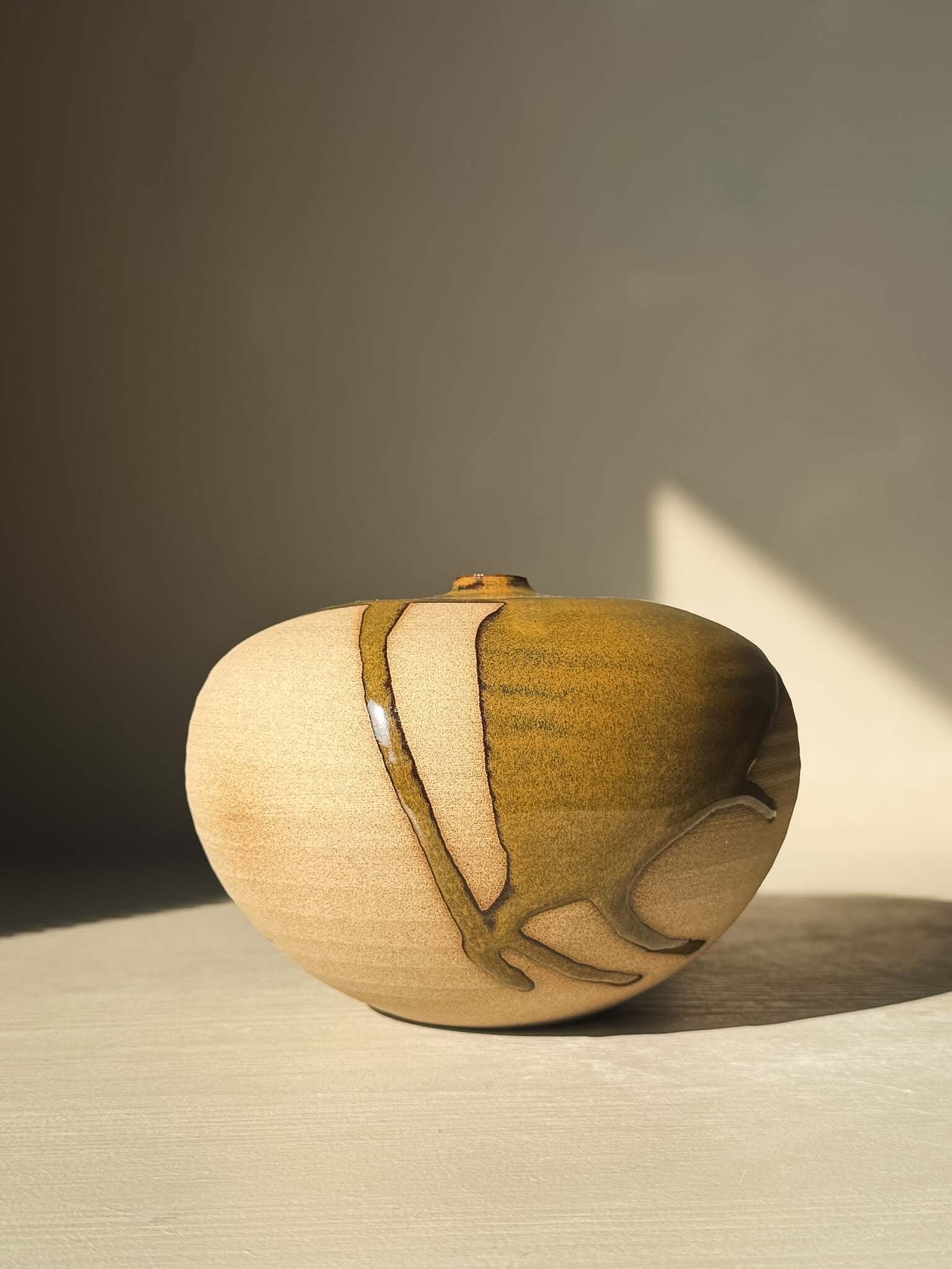 Orb Vase – #15 with unique glaze patterns and rounded form, showcasing natural drips on a calm, sculptural ceramic surface.