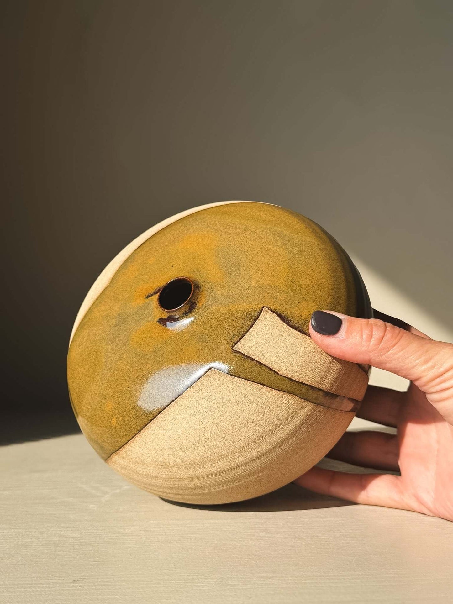 Hand holding Orb Vase – #15 with unique glaze pattern and rounded shape