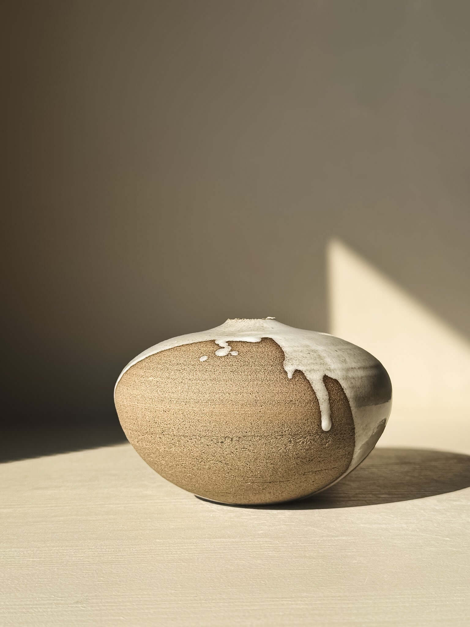 Orb Vase – #13 with unique glaze drips and sculptural form placed in natural light on a table.