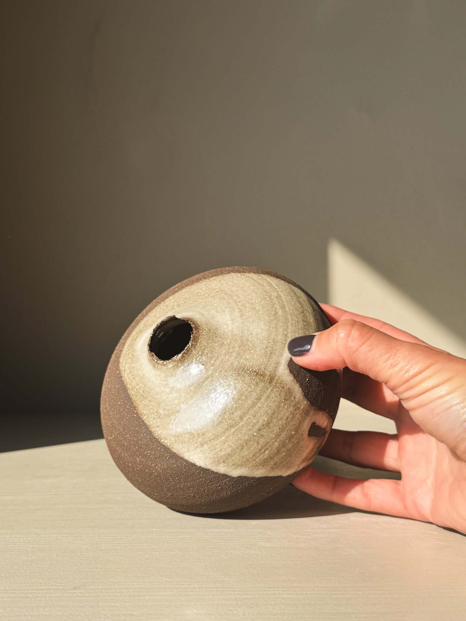 Hand holding Orb Vase – #12 with natural glaze patterns and unique spherical design