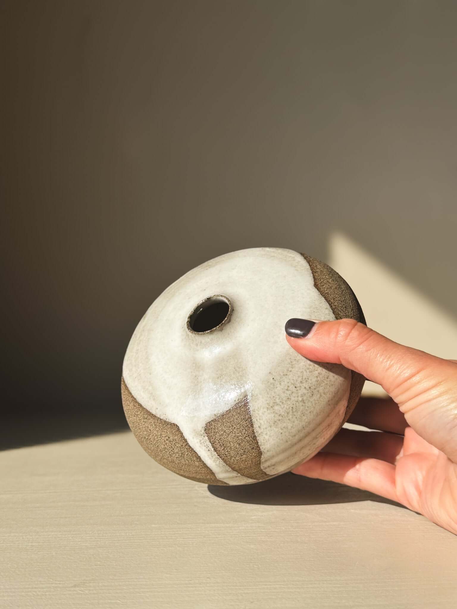Hand holding Orb Vase – #10 with unique glaze and rounded shape.