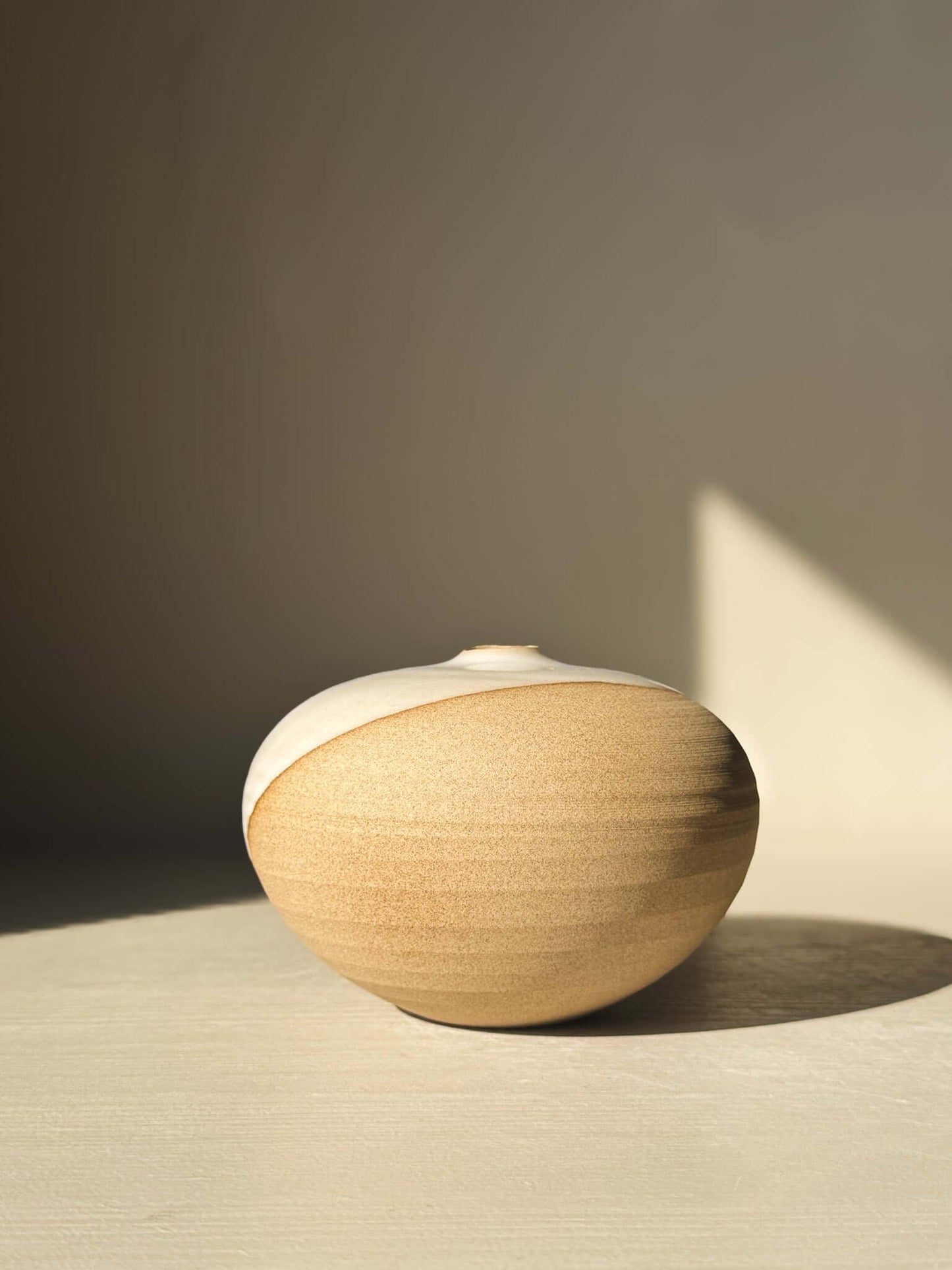 Orb Vase – #09 displayed in sunlight, showcasing its unique rounded shape and natural glaze patterns on a minimalist background.