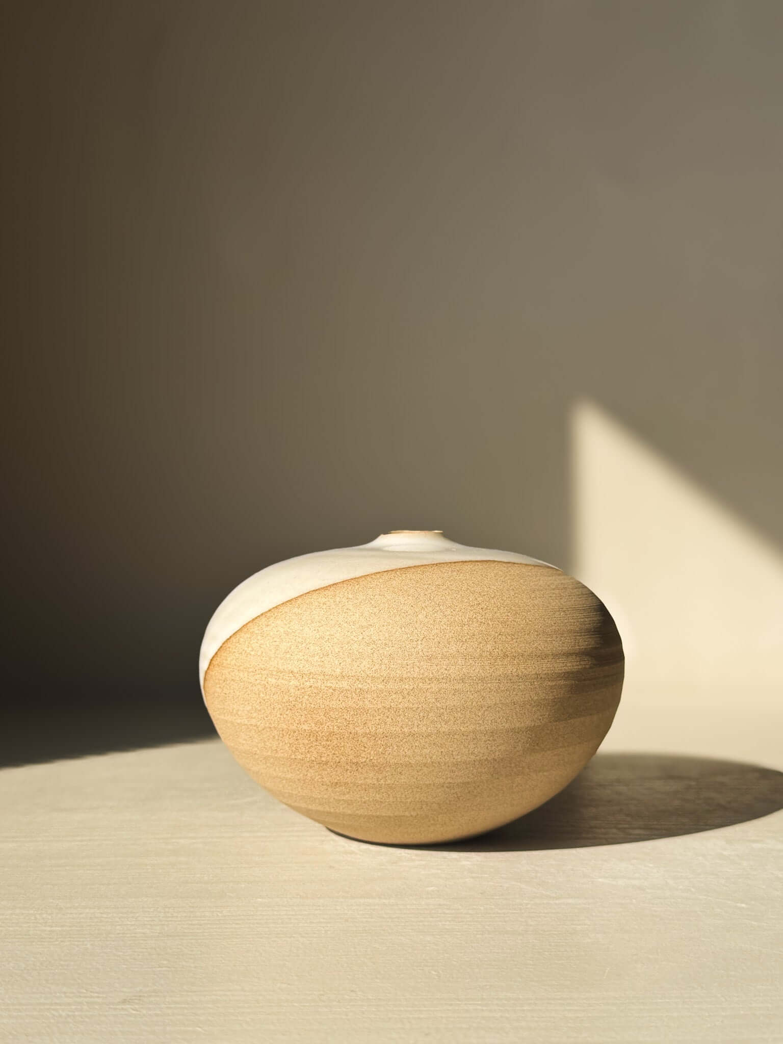 Orb Vase – #09 displayed in sunlight, showcasing its unique rounded shape and natural glaze patterns on a minimalist background.