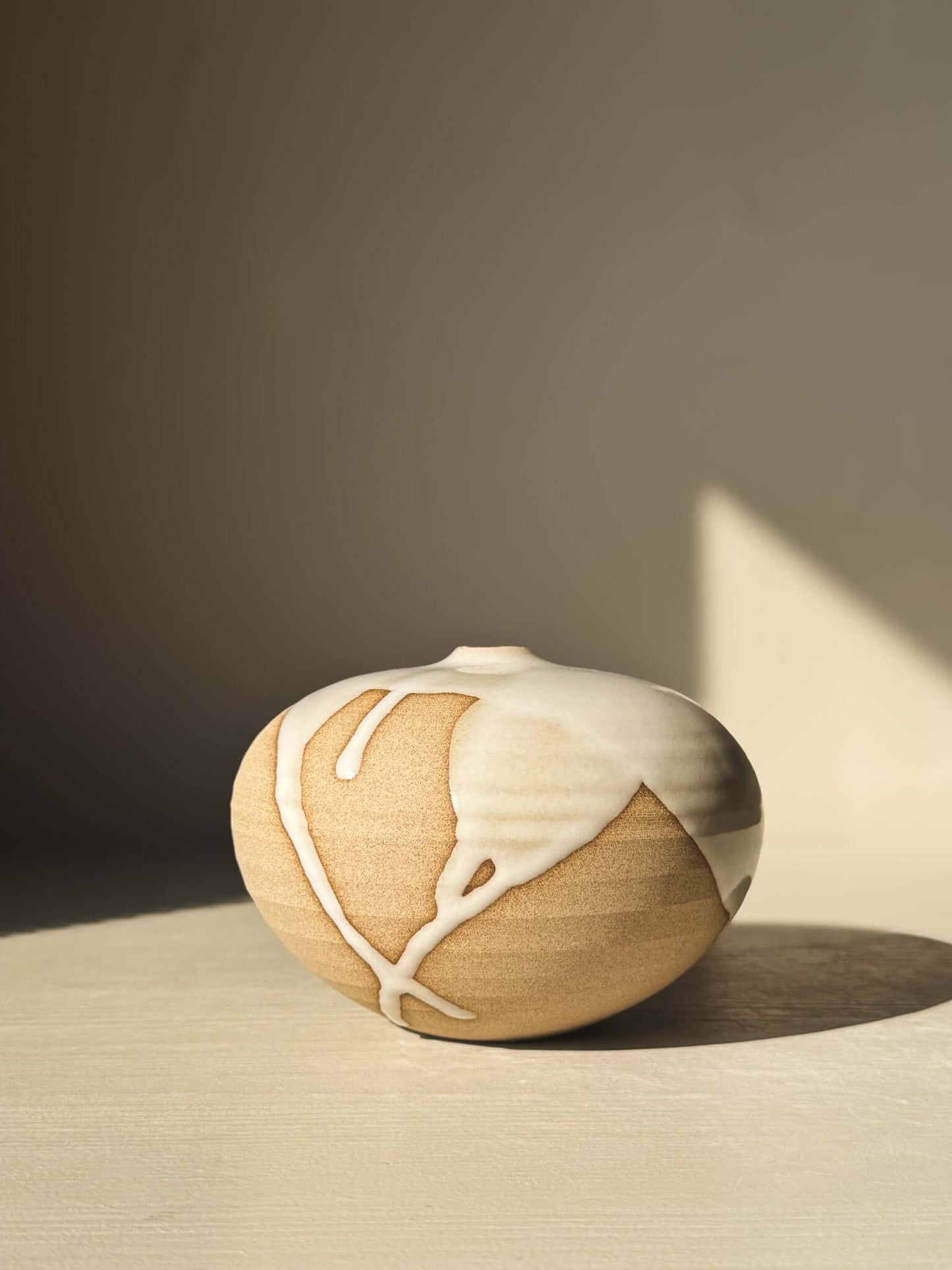 Orb Vase – #09 with natural glaze drips on a sculptural spherical form, showcasing unique clay texture and low rounded shape.