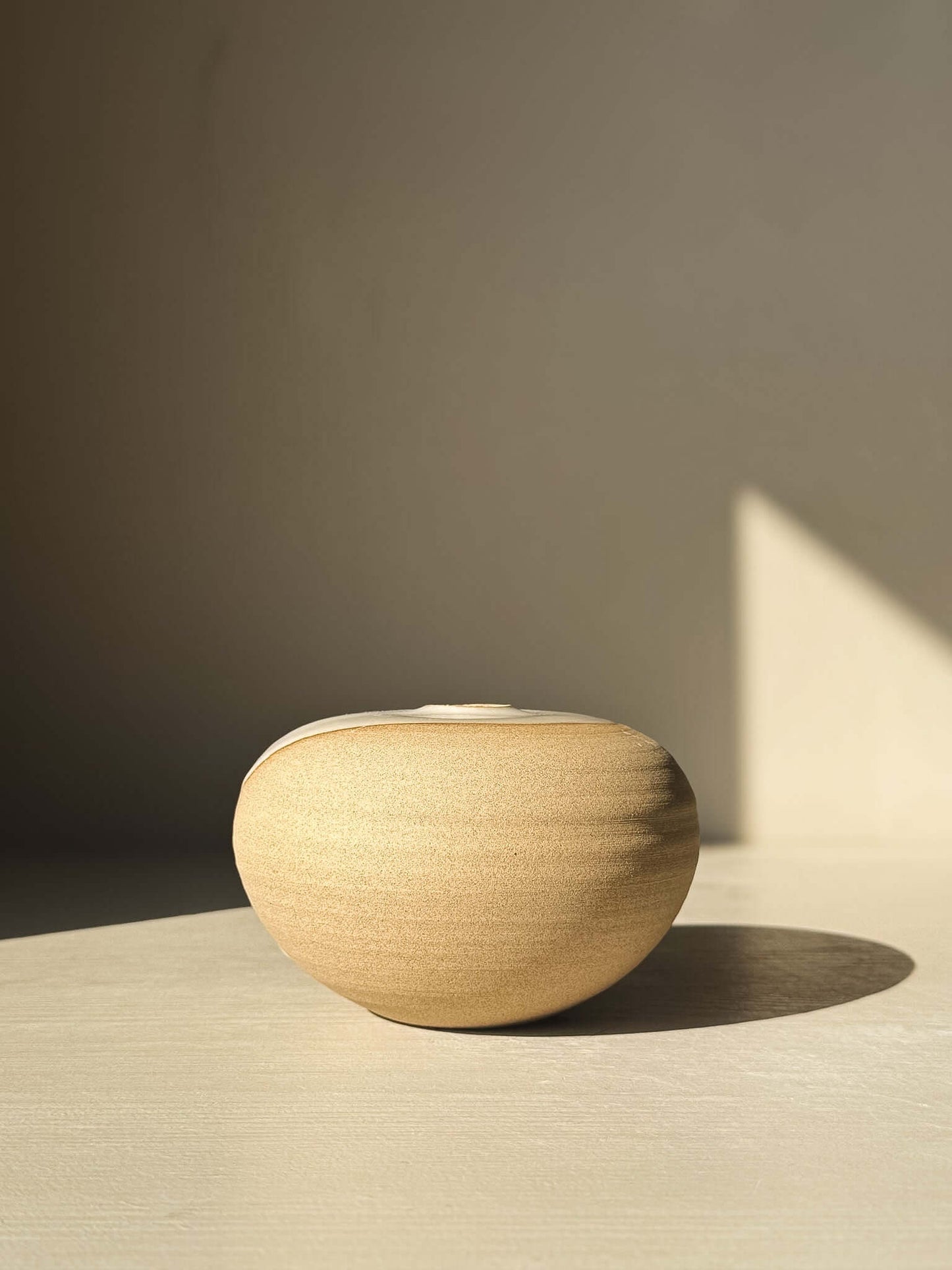 Orb Vase – #06 in soft sunlight, showcasing its smooth, rounded clay form and natural glaze patterns, part of a unique collection of vases.