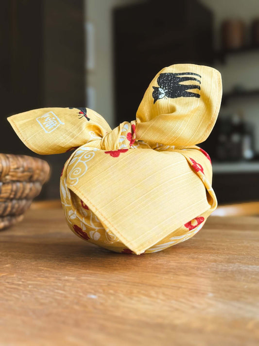 Small Furoshiki Yellow Cat Pattern tied in a bundle, featuring playful black cats and floral designs.
