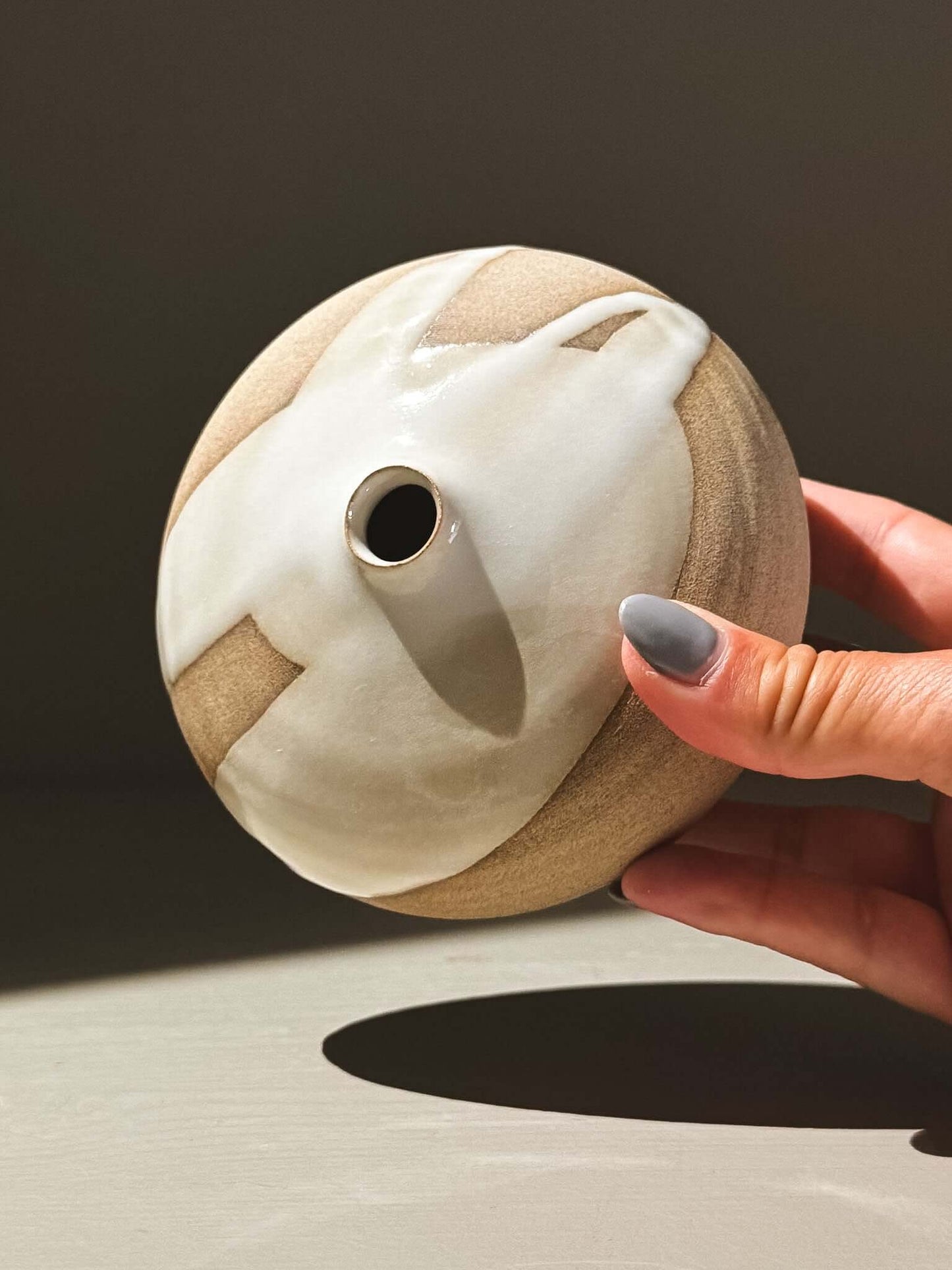 Orb Vase – Yuki #06 with unique glaze patterns, round form, and low opening held in hand.