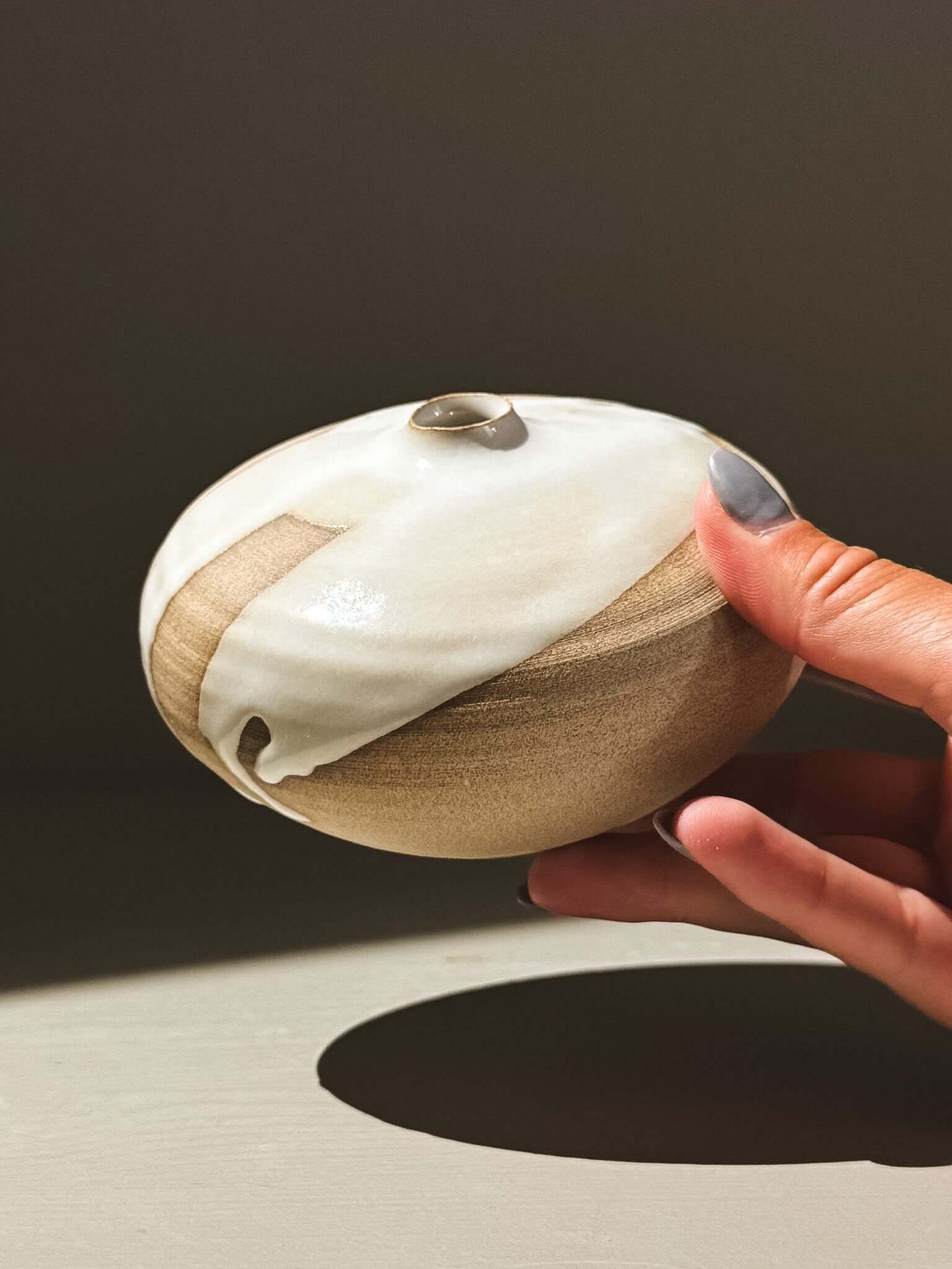 Orb Vase – Yuki #06 held in hand, showcasing its unique glaze and spherical form.