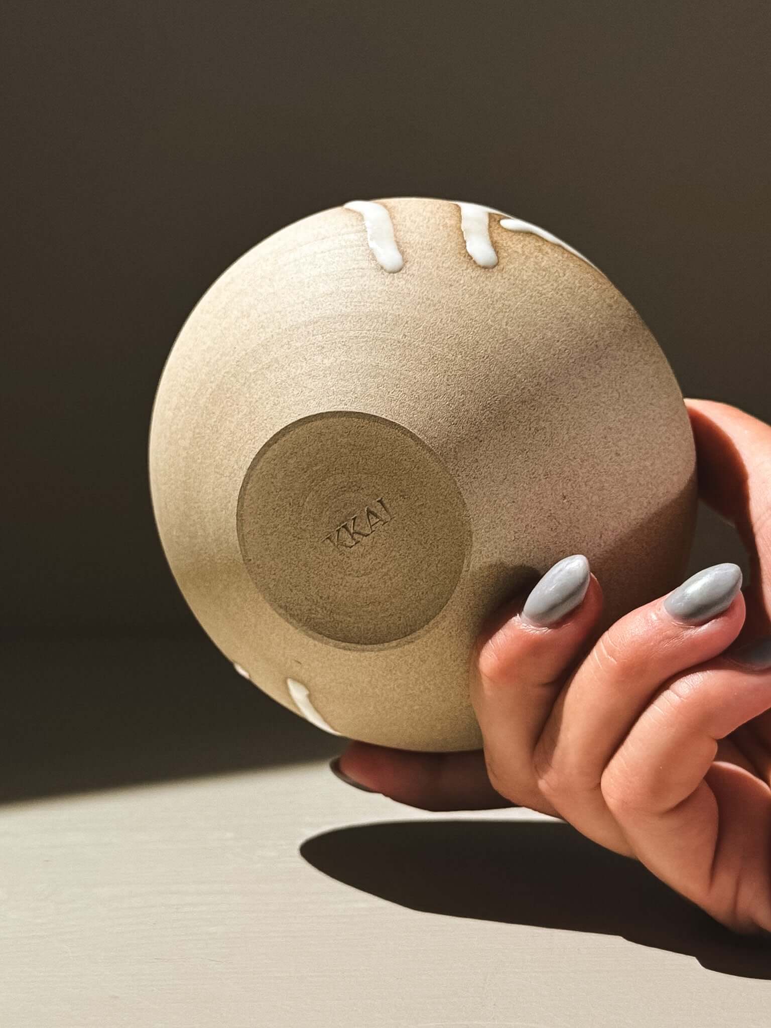 Orb Vase – Yuki #06 held in a hand, showcasing its unique glaze and rounded form.