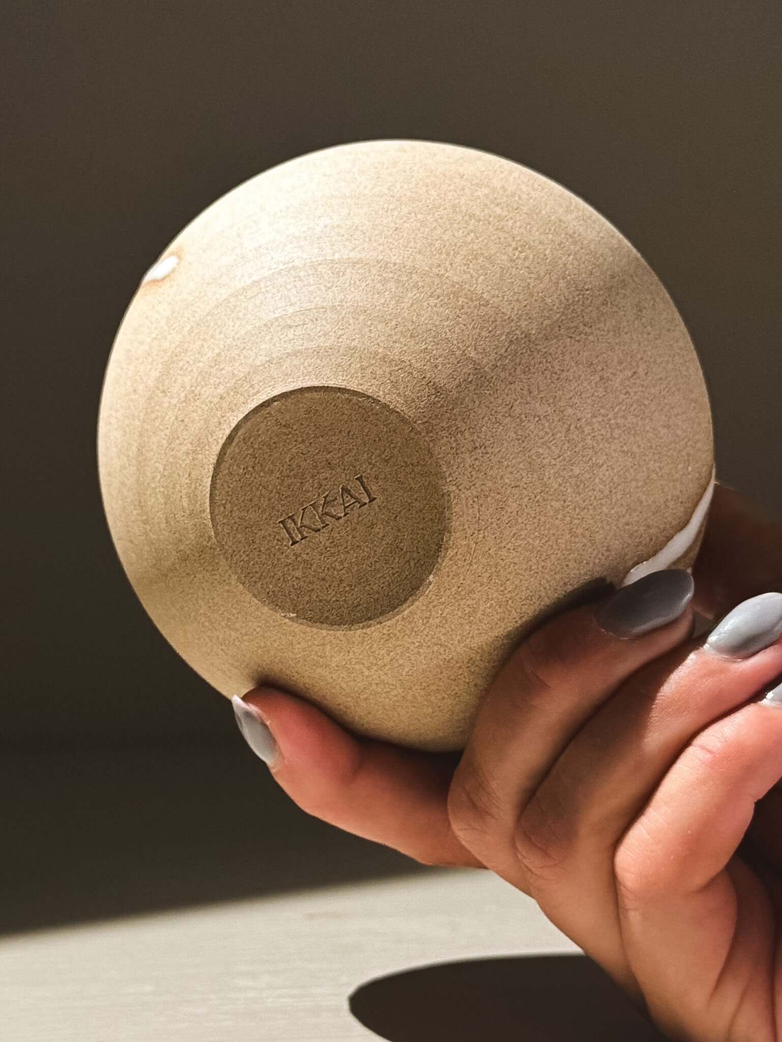 Orb Vase – Yuki #07 held elegantly, showcasing its smooth surface and unique glaze detailing.