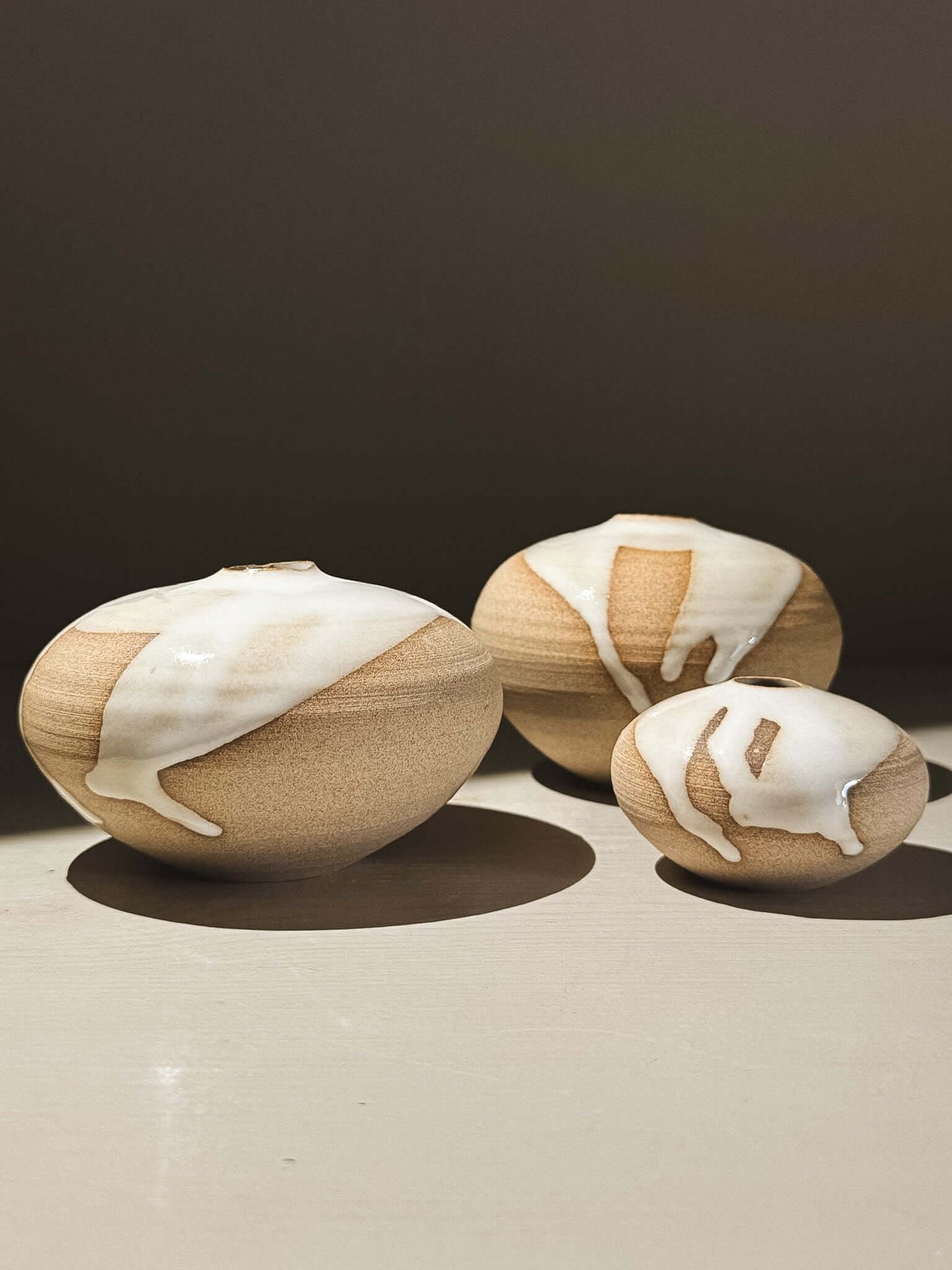 Orb Vase – Yuki #08, a trio of rounded vases with unique glaze patterns and soft, sculptural forms.