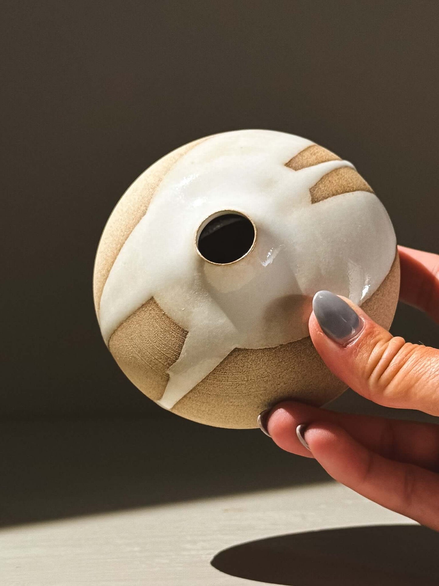 Hand holding an Orb Vase – Yuki #09 showcasing its unique glaze patterns and soft spherical form.