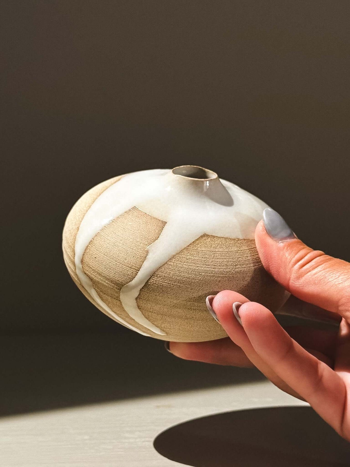 Hand holding an Orb Vase – Yuki #09 showcasing its unique clay and glaze patterns.