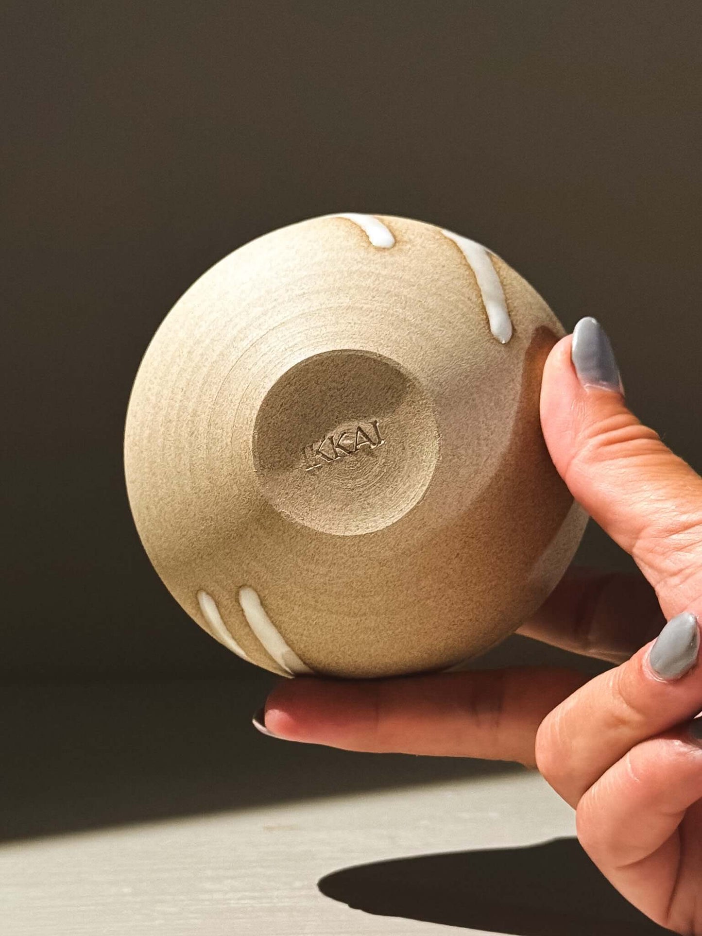 Hand holding the Orb Vase – Yuki #09 showcasing its unique glaze and rounded form.
