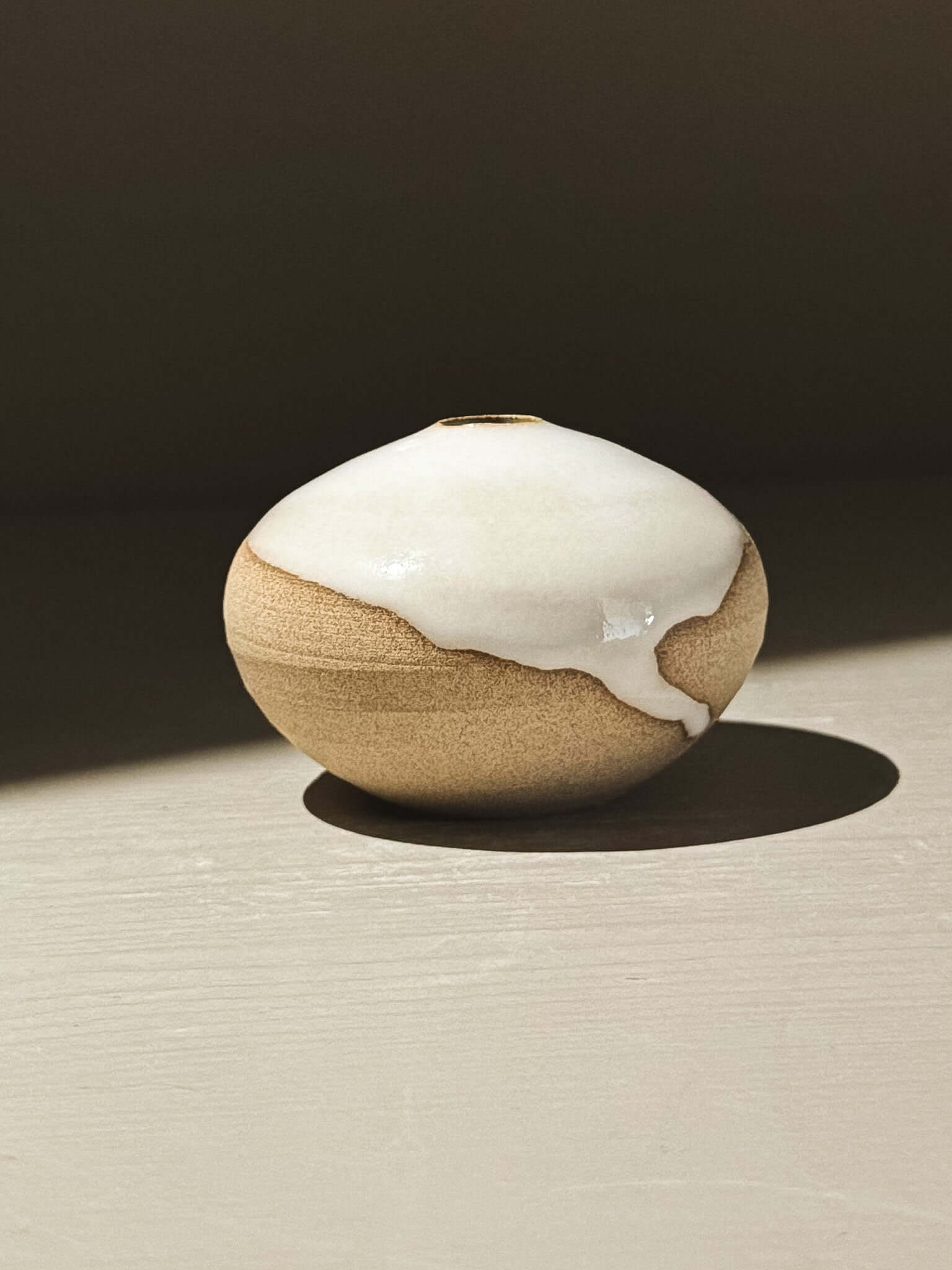 Orb Vase – Yuki #12 displayed on a surface, featuring a soft spherical form and unique glaze patterns.