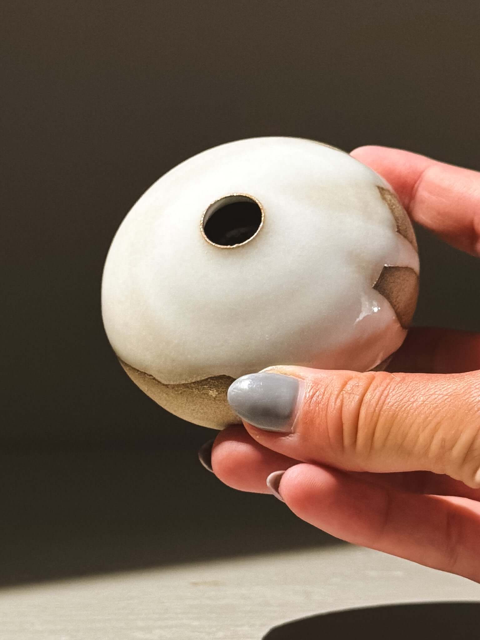 Hand holding an Orb Vase – Yuki #12 showcasing its unique glaze and rounded design.
