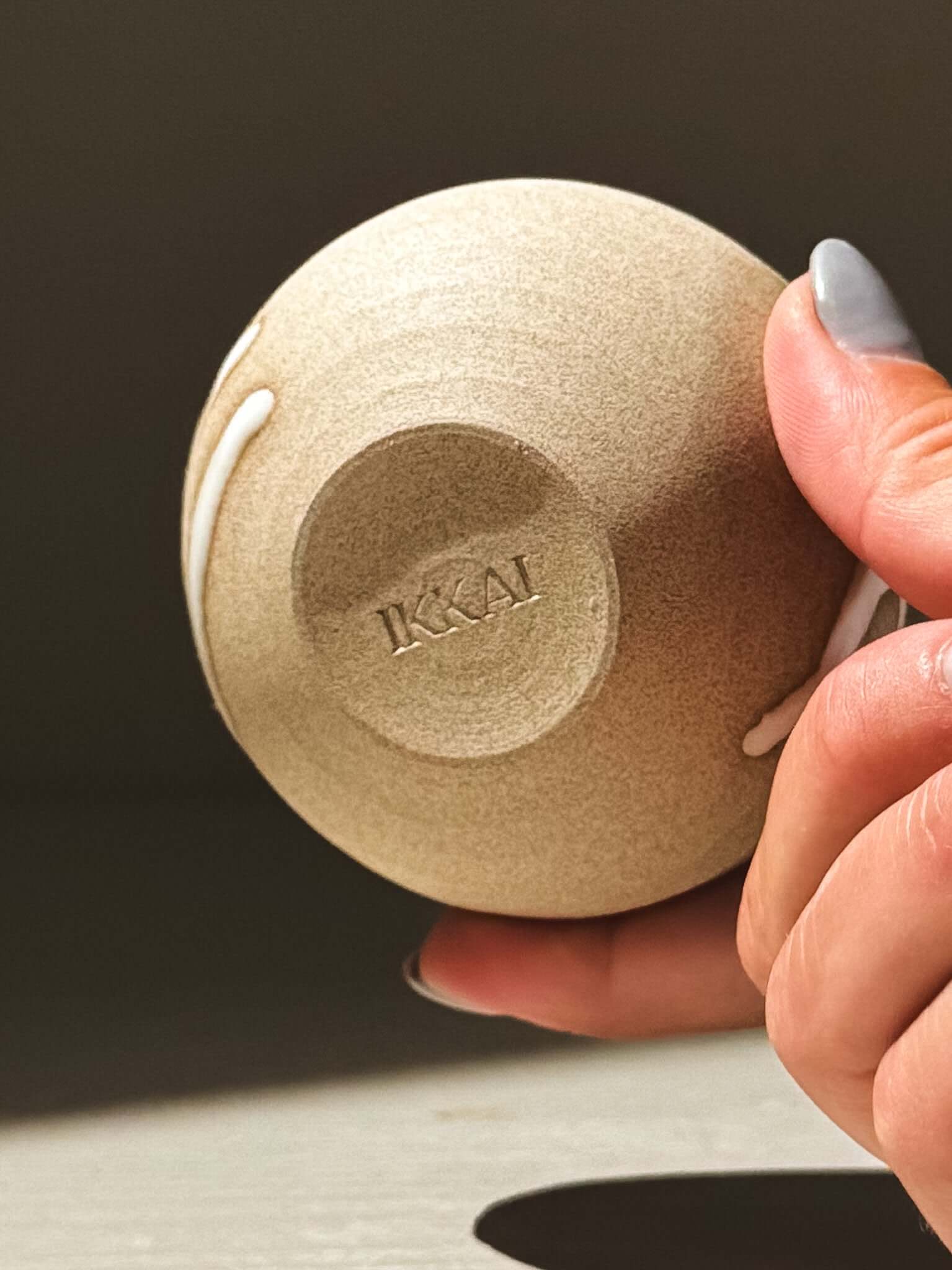 Orb Vase – Yuki #12 held in hand, showcasing unique glaze and rounded form with K&AI imprint on base.
