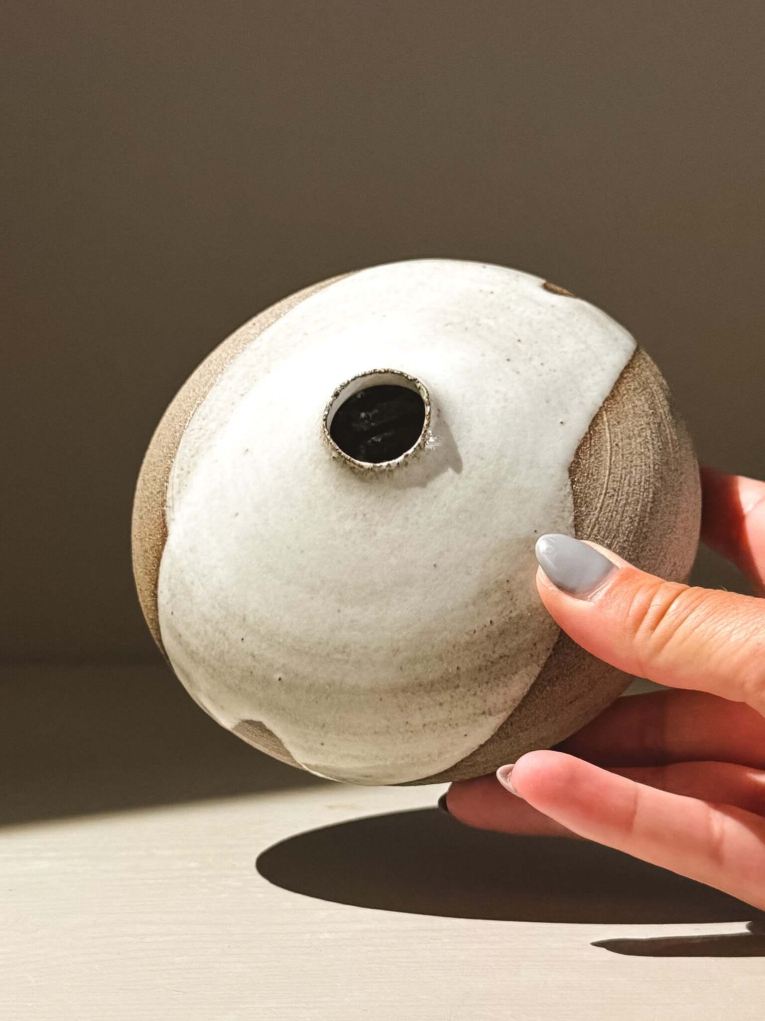 Hand holding an Orb Vase – Yuki Ash #03, featuring a unique glaze design and soft spherical form.