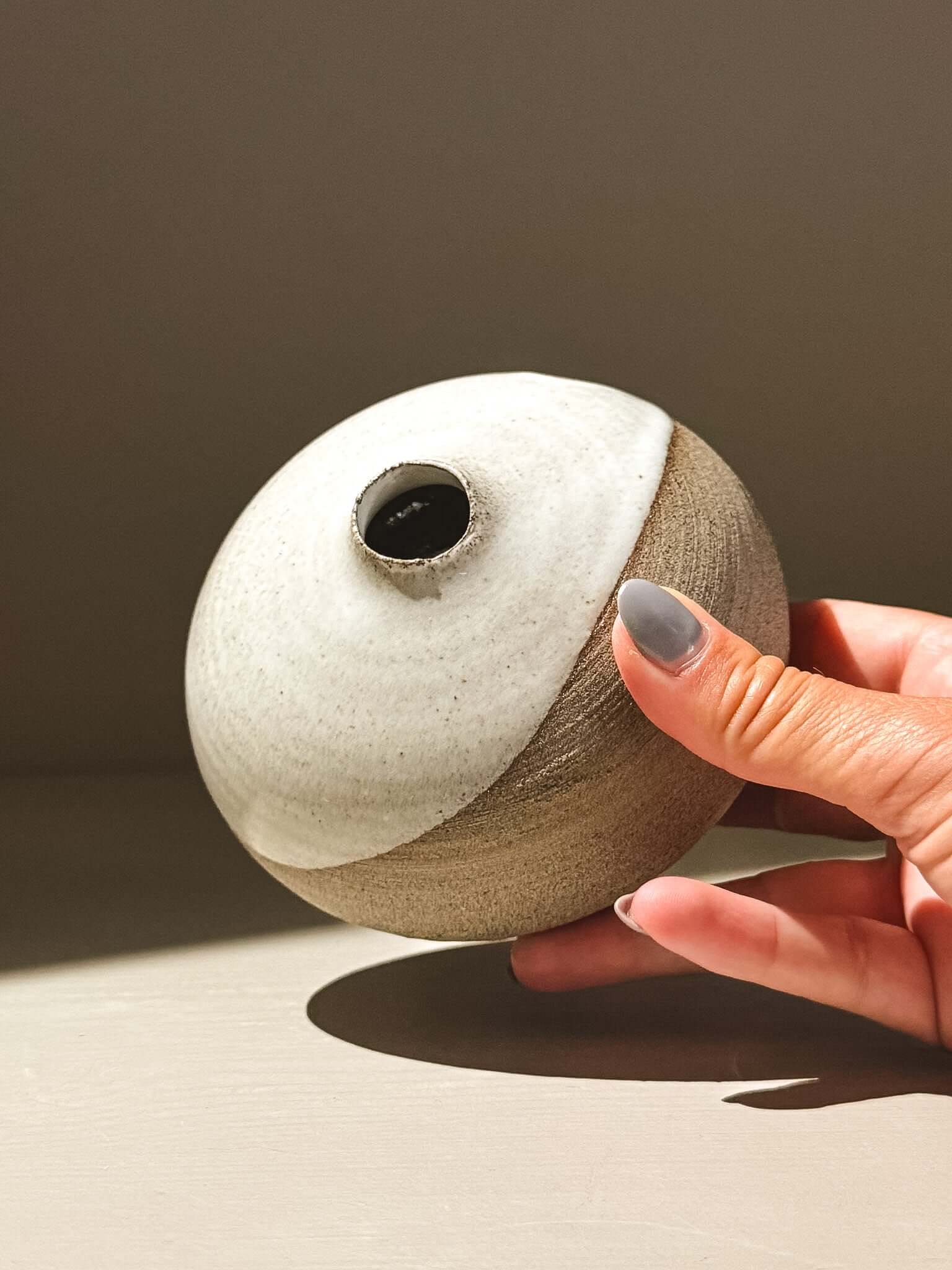 Orb Vase – Yuki Ash #06 held in hand, showcasing unique glaze patterns and soft spherical form.