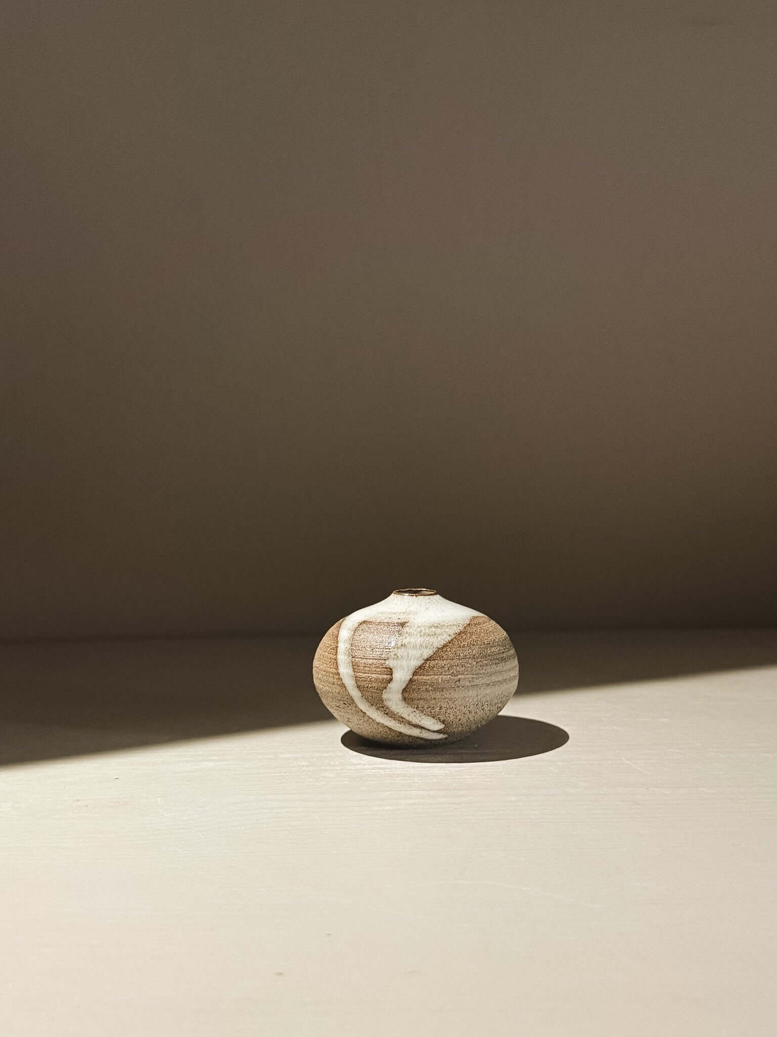 Handmade ceramic Japanese orb vase, Orb Vase – Yuki Ash #16, showcasing unique glaze patterns and soft spherical form.