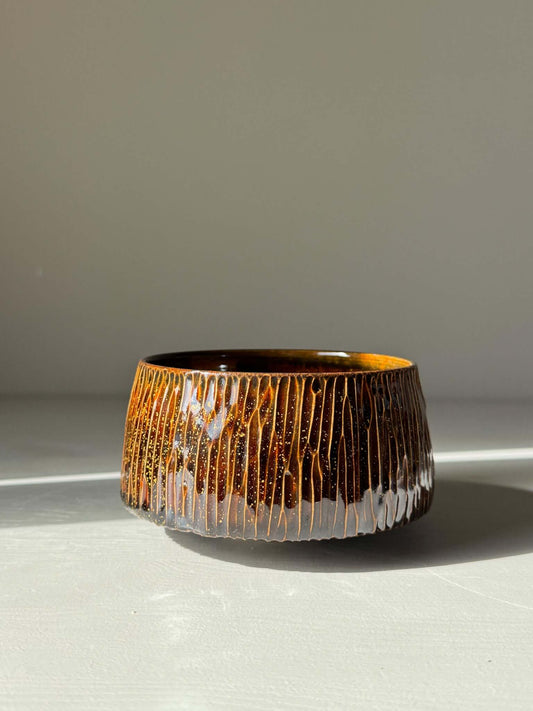 Matcha Bowl – Kinsei #03, handmade ceramic with a glossy brown exterior and gold spiral interior, glowing like a galaxy inside.