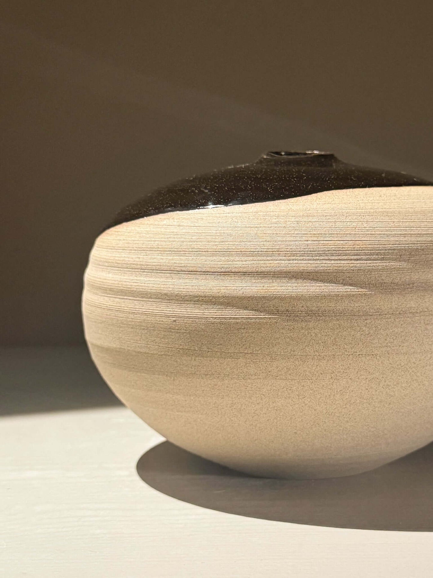 Orb Vase – Kuro #0 showcasing unique clay and organic glaze patterns in a sculptural rounded form.