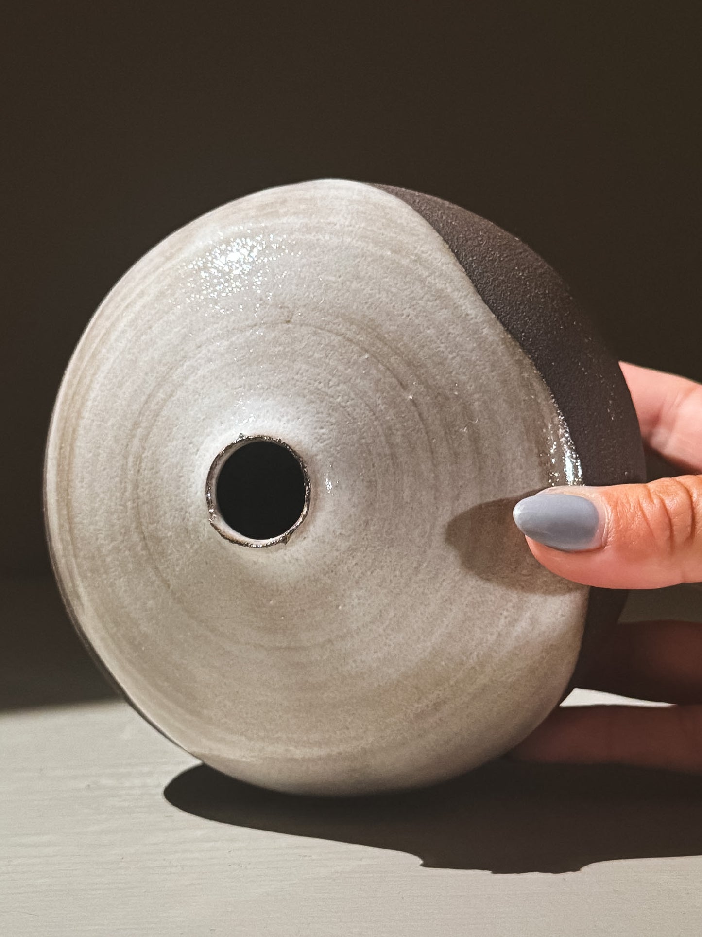 Orb Vase – Yuki Black #02, a rounded ceramic vase with a smooth glaze and small opening, held by a hand.