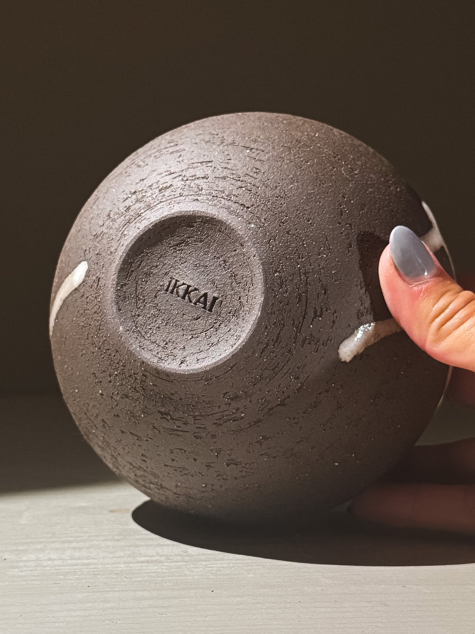 Close-up of the base of the orb vase 'Yuki Black #02' showcasing its unique glaze and finish.