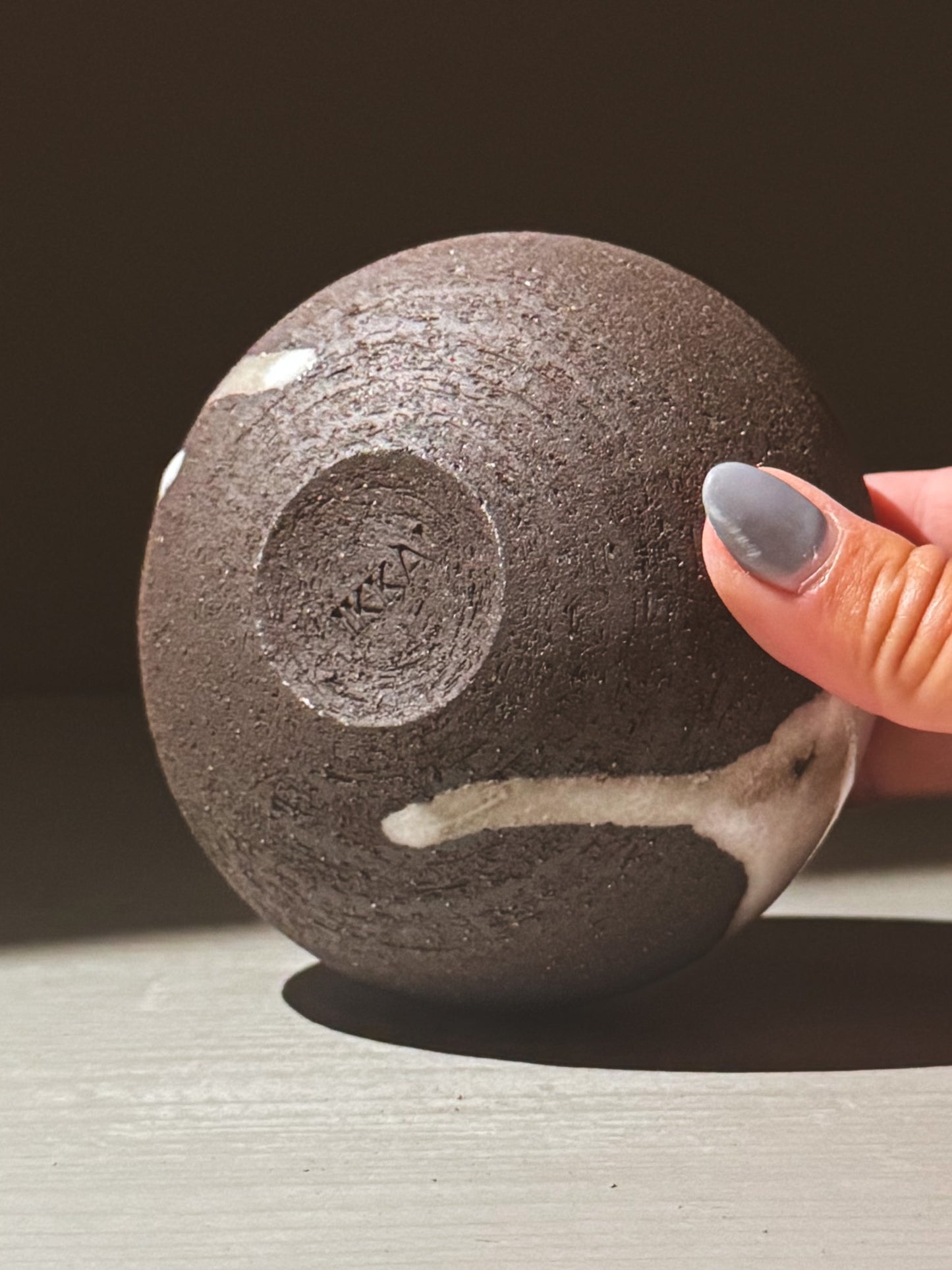Orb Vase – Yuki Black #12 held in hand, showcasing unique glaze patterns and rounded shape.