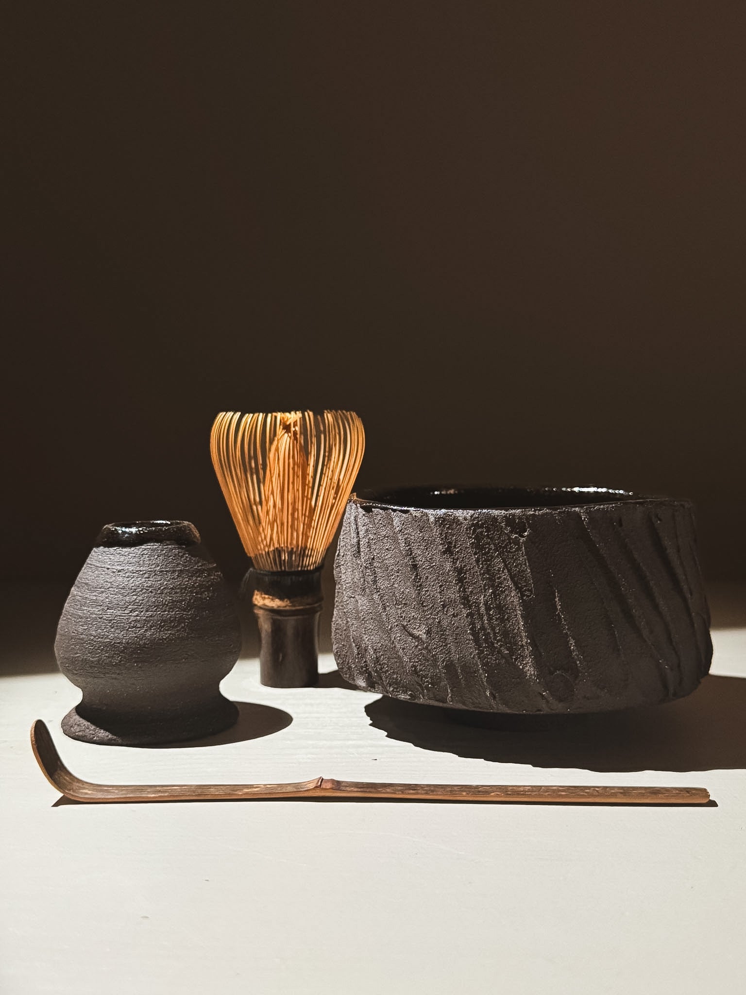 Kuro Matcha Bowl #06 with textured exterior and glossy interior, alongside matcha whisk and scoop.