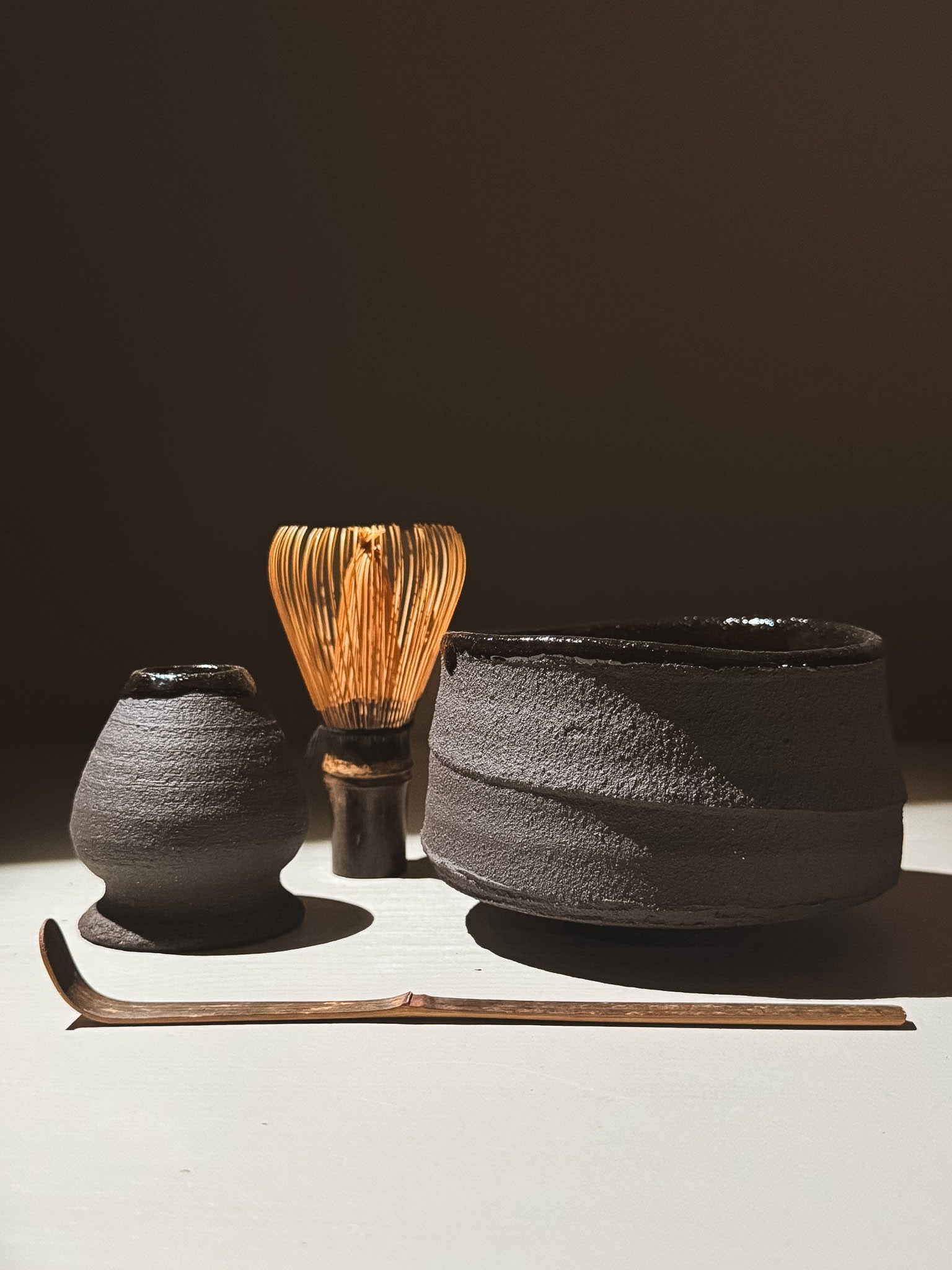 Kuro Matcha Bowl #09 with traditional matcha tools including a whisk and scoop, showcasing earthy textures and glossy glaze.