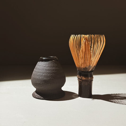 Whisk Holder  - Kuro beside a traditional matcha whisk, showcasing earthy tones and glossy finishes.