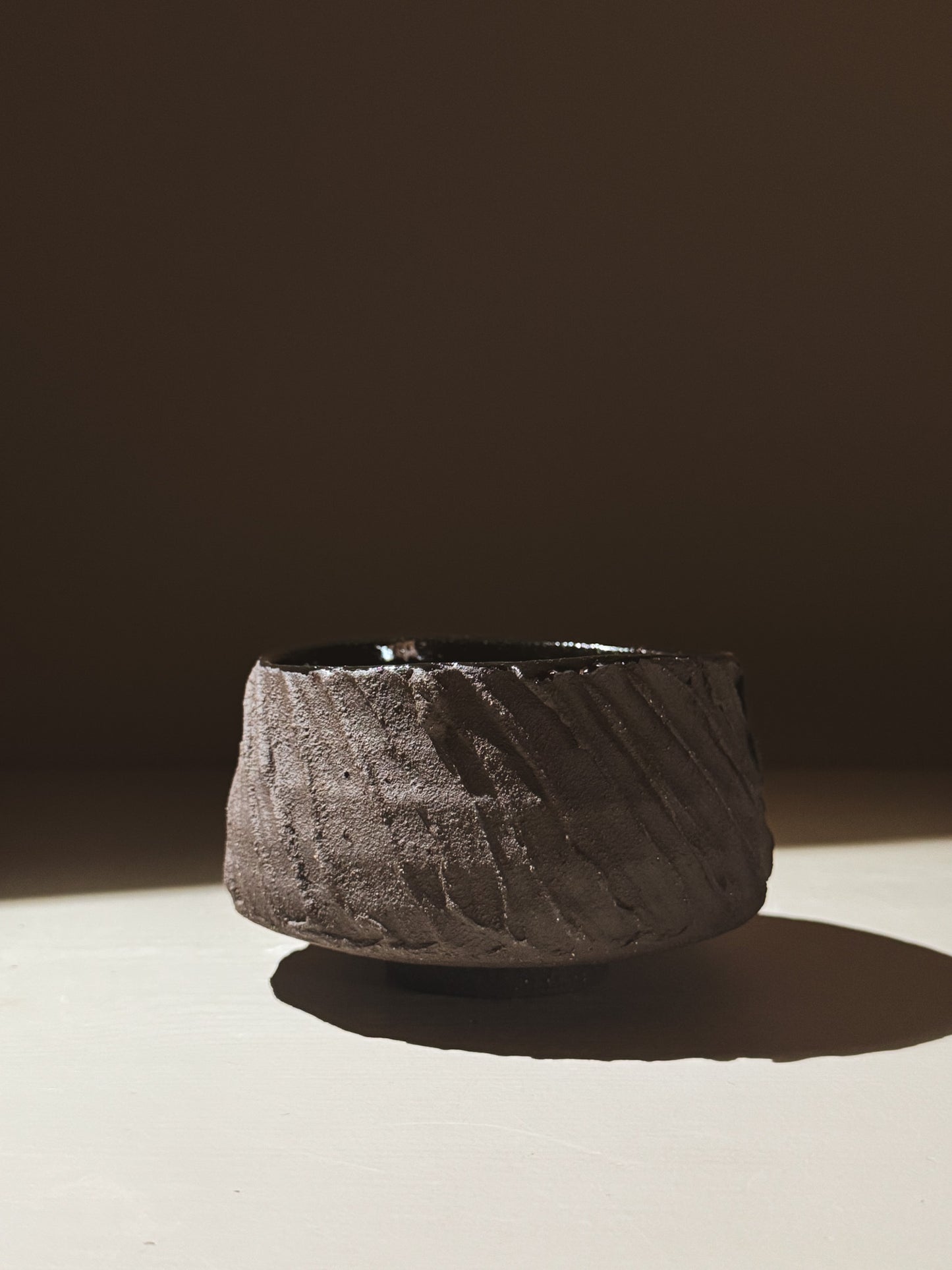 Kuro Matcha Bowl #01 featuring a textured dark brown exterior and glossy black interior, inspired by volcanic stone.