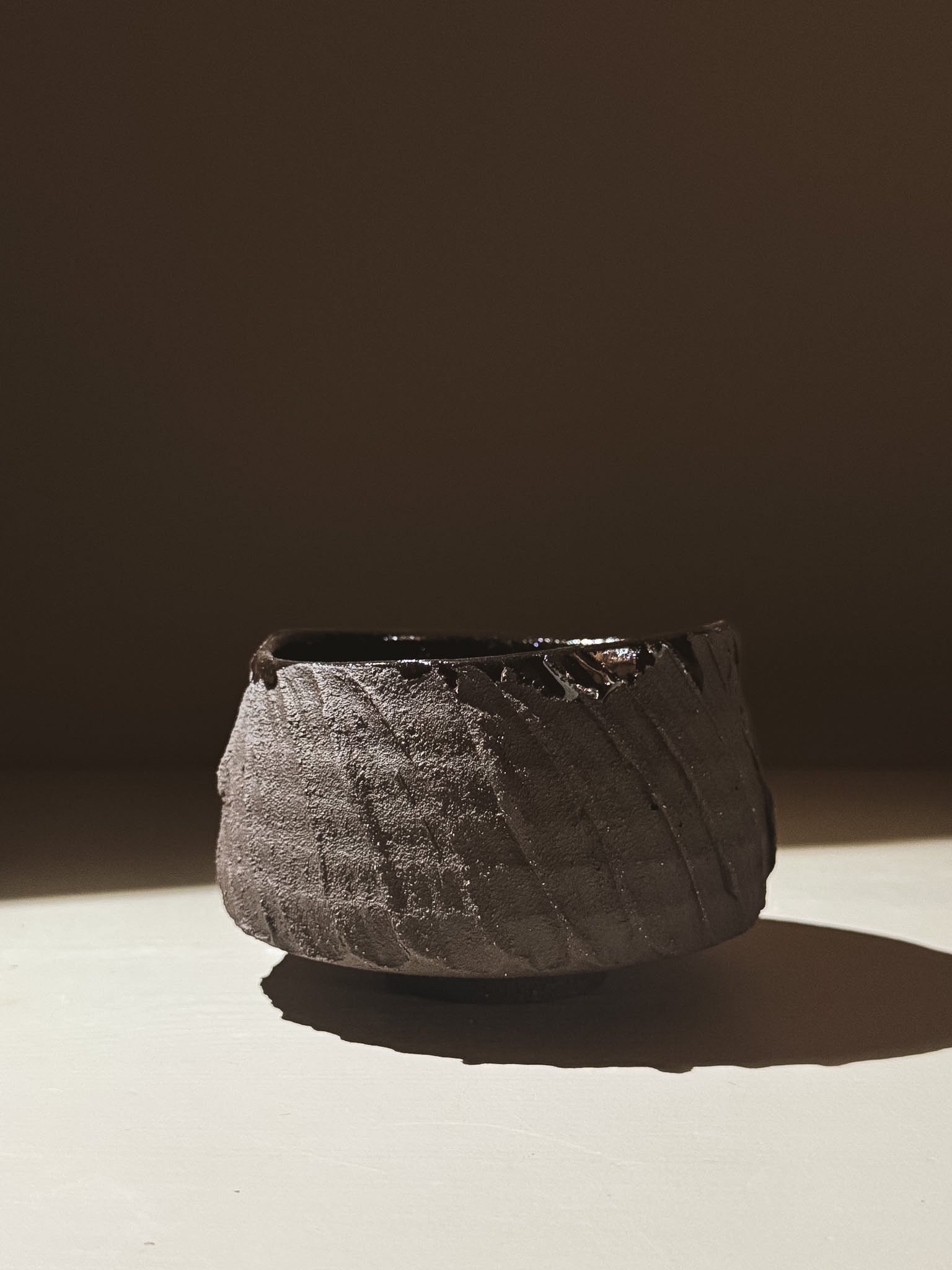 Kuro Matcha Bowl #02 showcasing a textured dark brown exterior and glossy interior, inspired by volcanic stone.