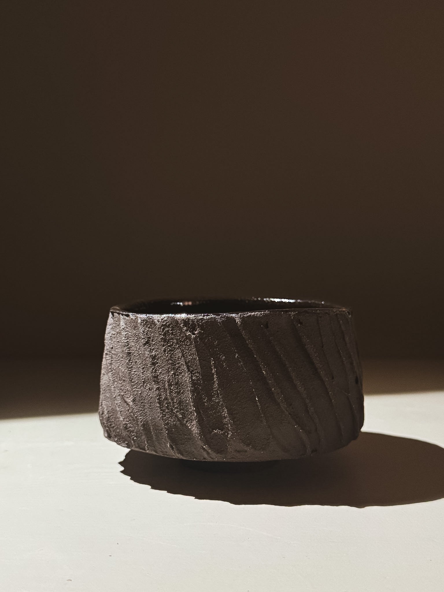 Kuro Matcha Bowl #06 with textured dark brown exterior and glossy interior in natural lighting.