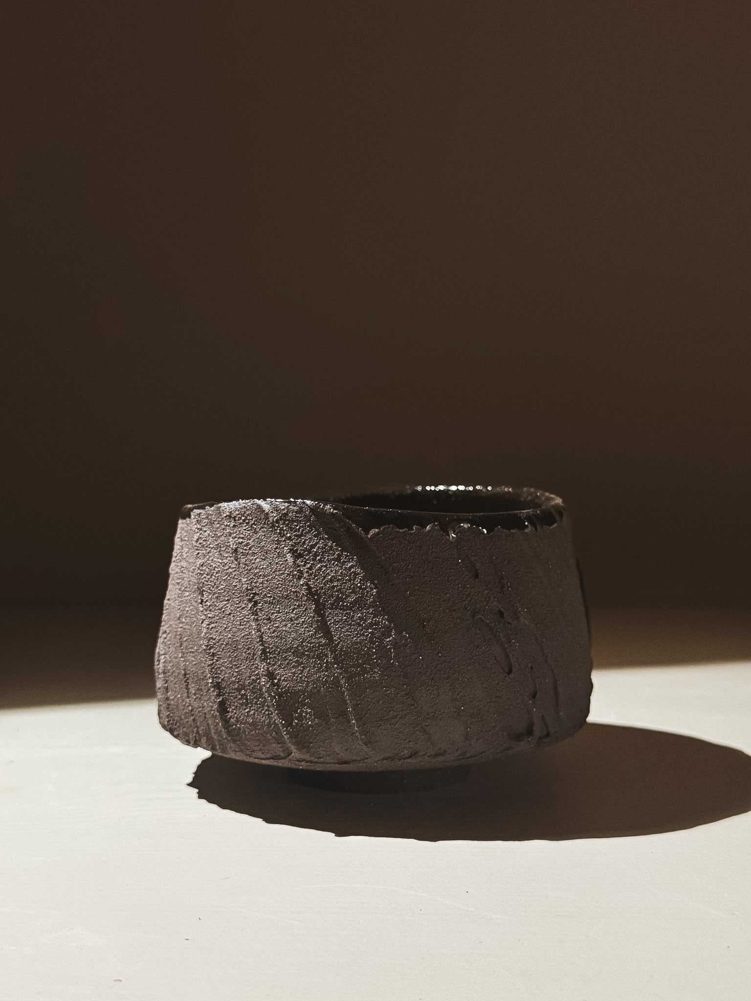Kuro Matcha Bowl #07 showcasing volcanic stone inspiration with textured dark exterior and glossy interior.