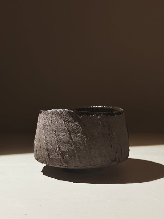 Kuro Matcha Bowl #07 showcasing volcanic stone inspiration with textured dark exterior and glossy interior.
