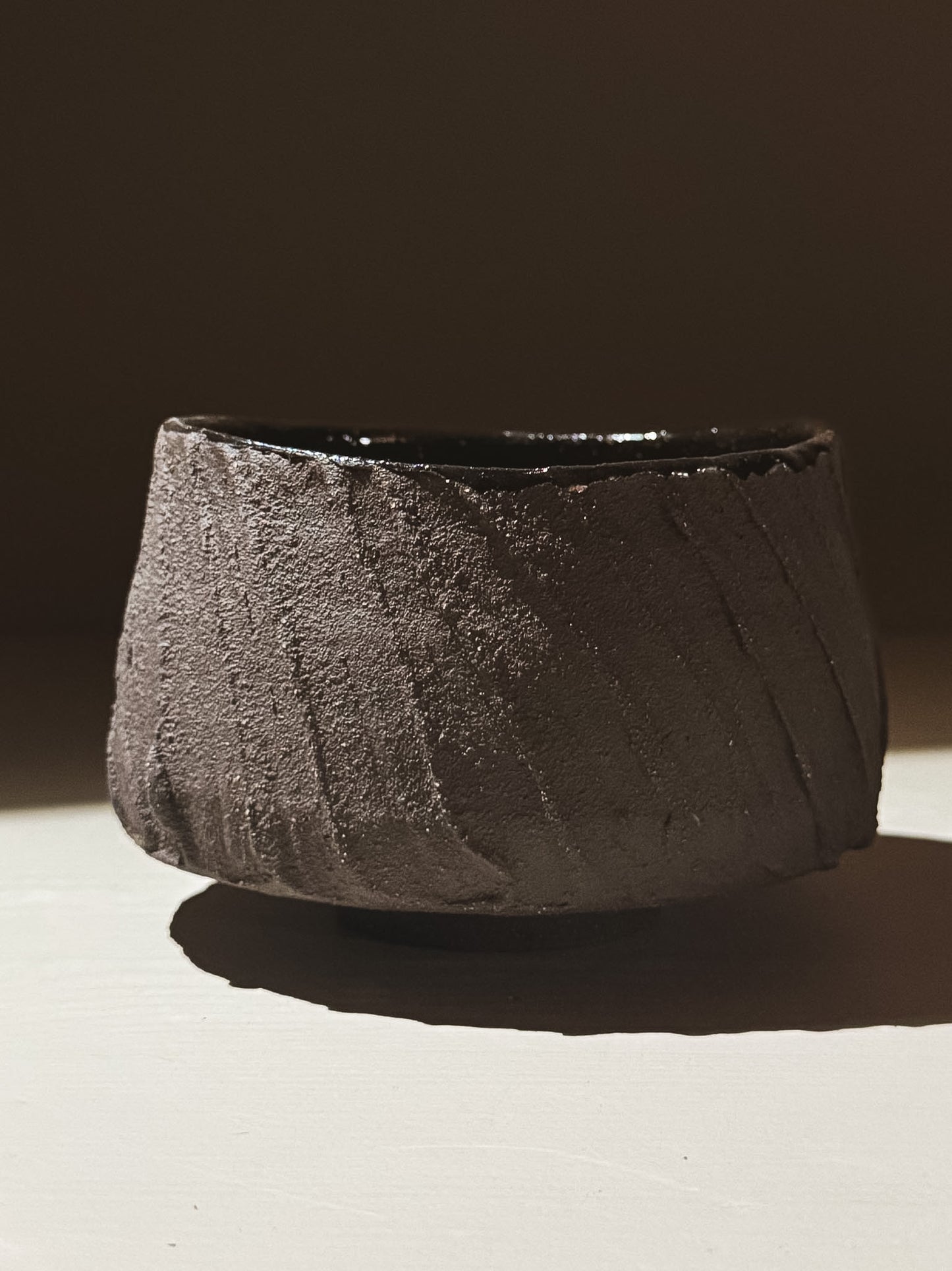 Close-up of the Kuro Matcha Bowl #07 showcasing its textured dark exterior and glossy interior glaze.