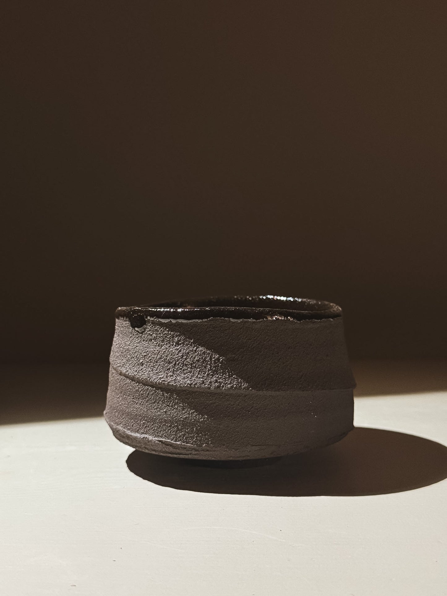 Kuro Matcha Bowl #09 featuring textured dark brown exterior and glossy dark interior under soft light.