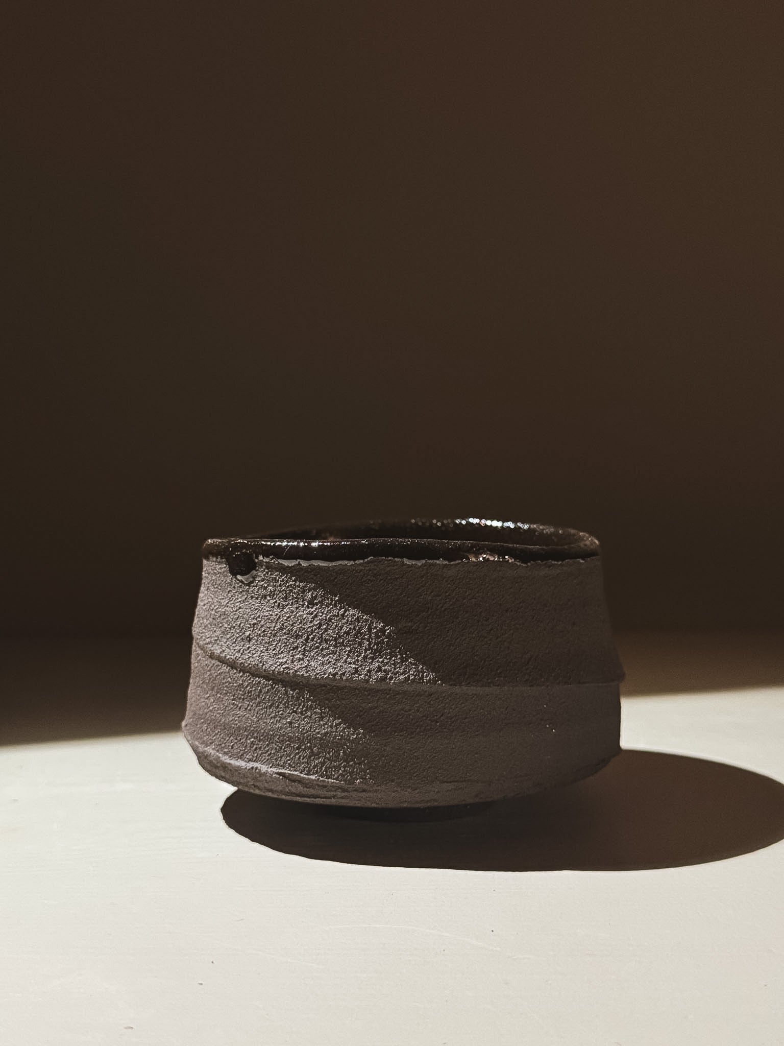 Kuro Matcha Bowl #09 featuring textured dark brown exterior and glossy dark interior under soft light.
