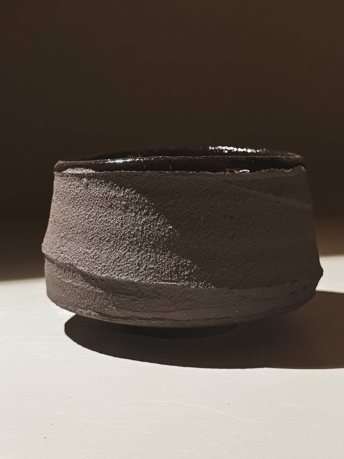 Kuro Matcha Bowl #09 showcasing volcanic stone design with textured dark brown slip and glossy dark glaze.