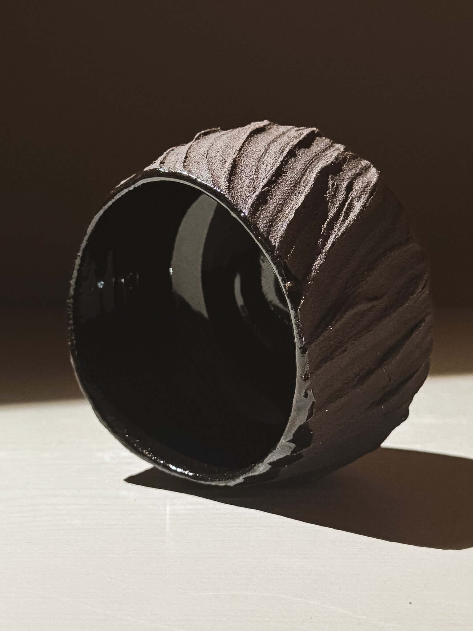 Yunomi Cup - Kuro #01 showcasing textured dark brown clay exterior and shiny glossy black interior.