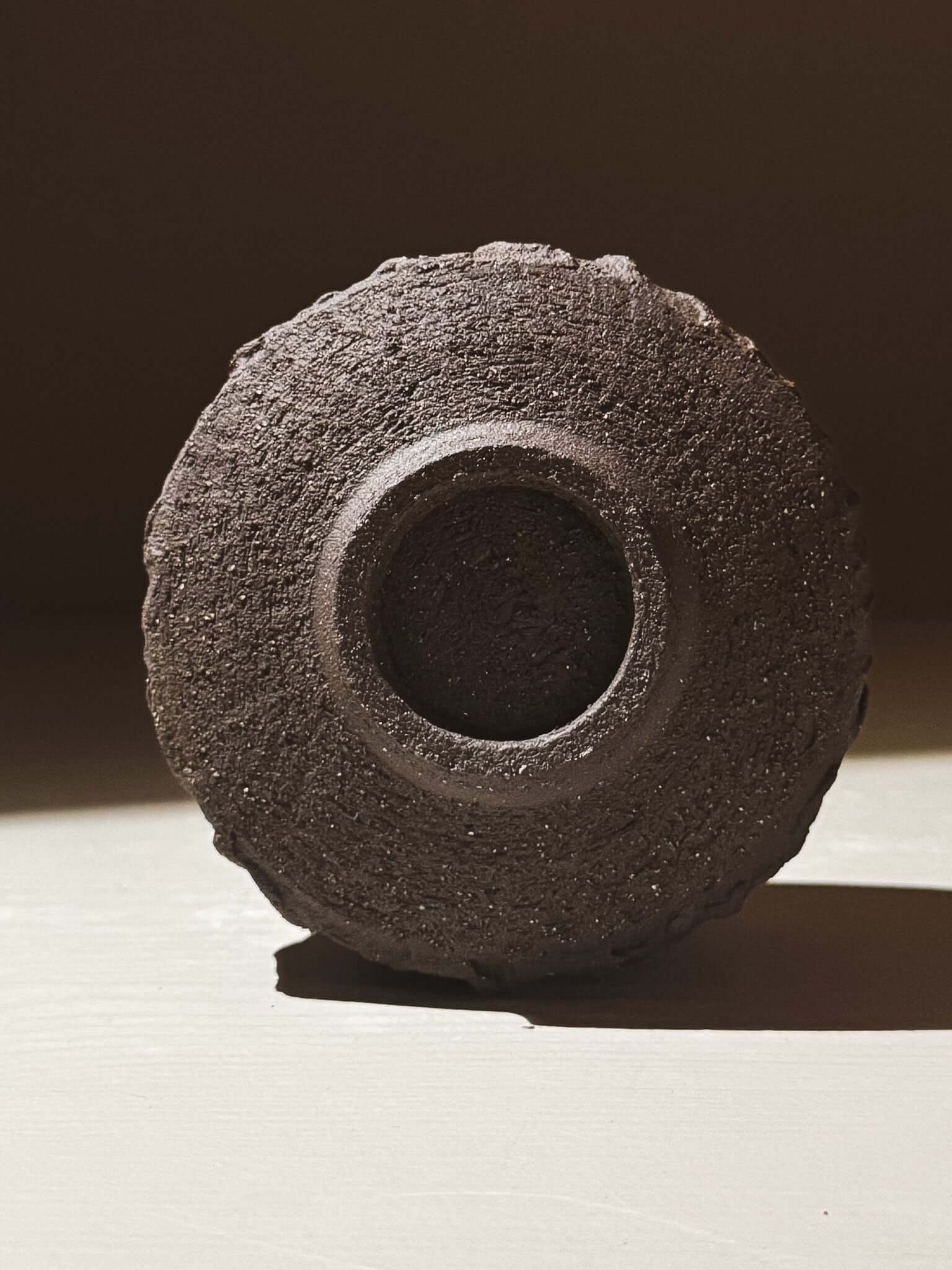 Bottom view of Yunomi Cup - Kuro #01 showcasing textured dark brown clay and earthy design.
