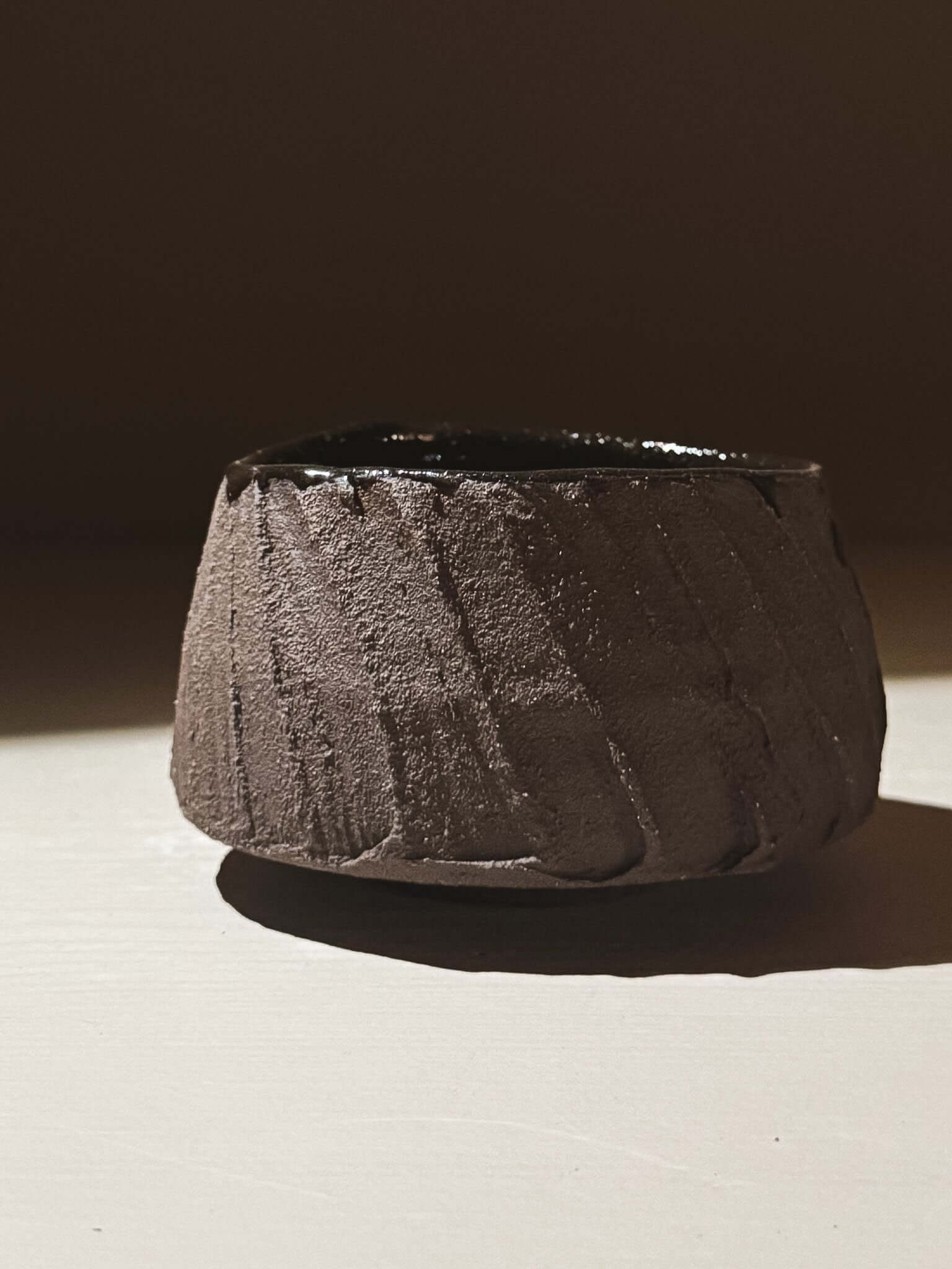Yunomi Cup - Kuro #02 with textured dark brown clay and glossy dark glaze, showcasing earthy tones and volcanic stone inspiration.