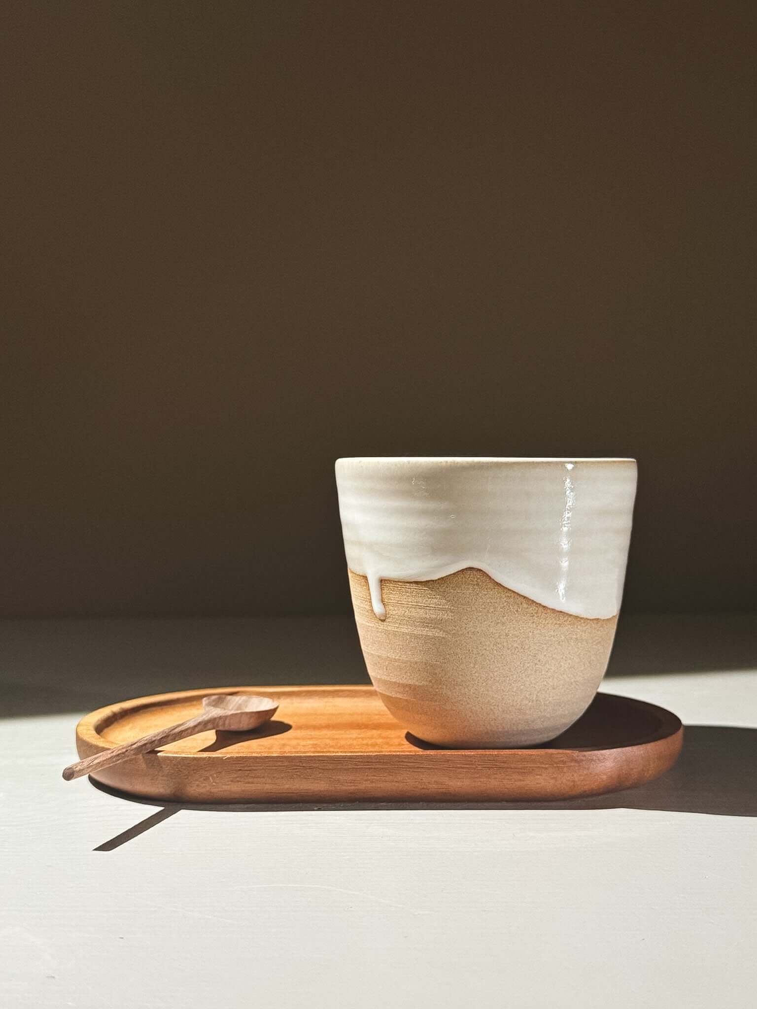 Stackable Latte Cups - Yuki resting on a wooden tray with a small spoon, showcasing a glossy white and warm toffee glaze.