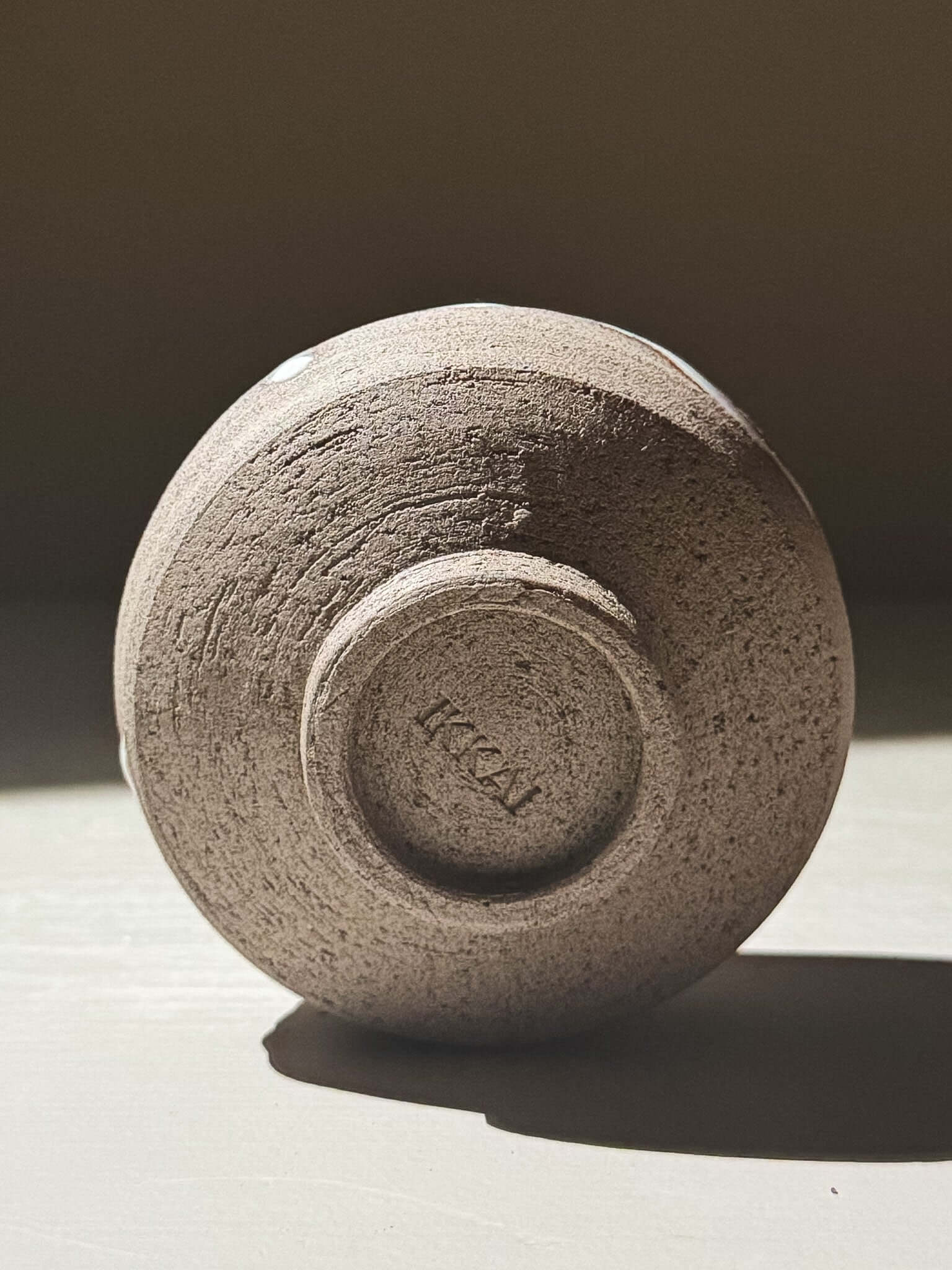 Yunomi Cup - Yuki Ash #02 showing the underside with textured clay and signature mark.